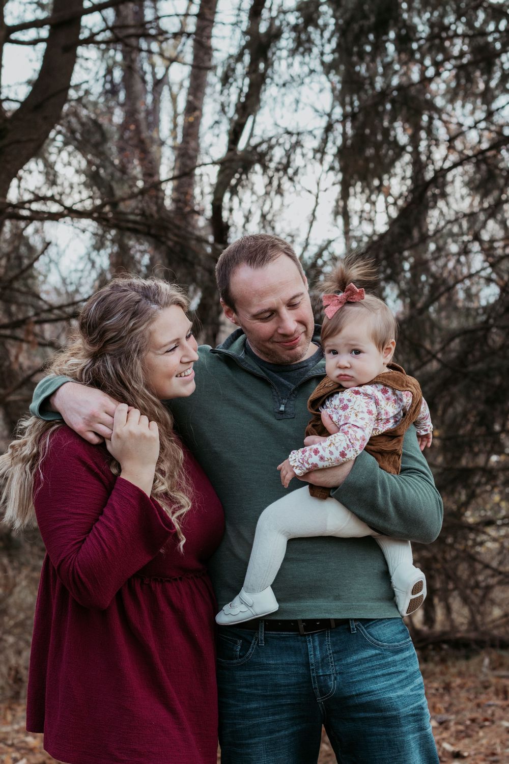 Family sharing playful moments together in an autumn forest setting.