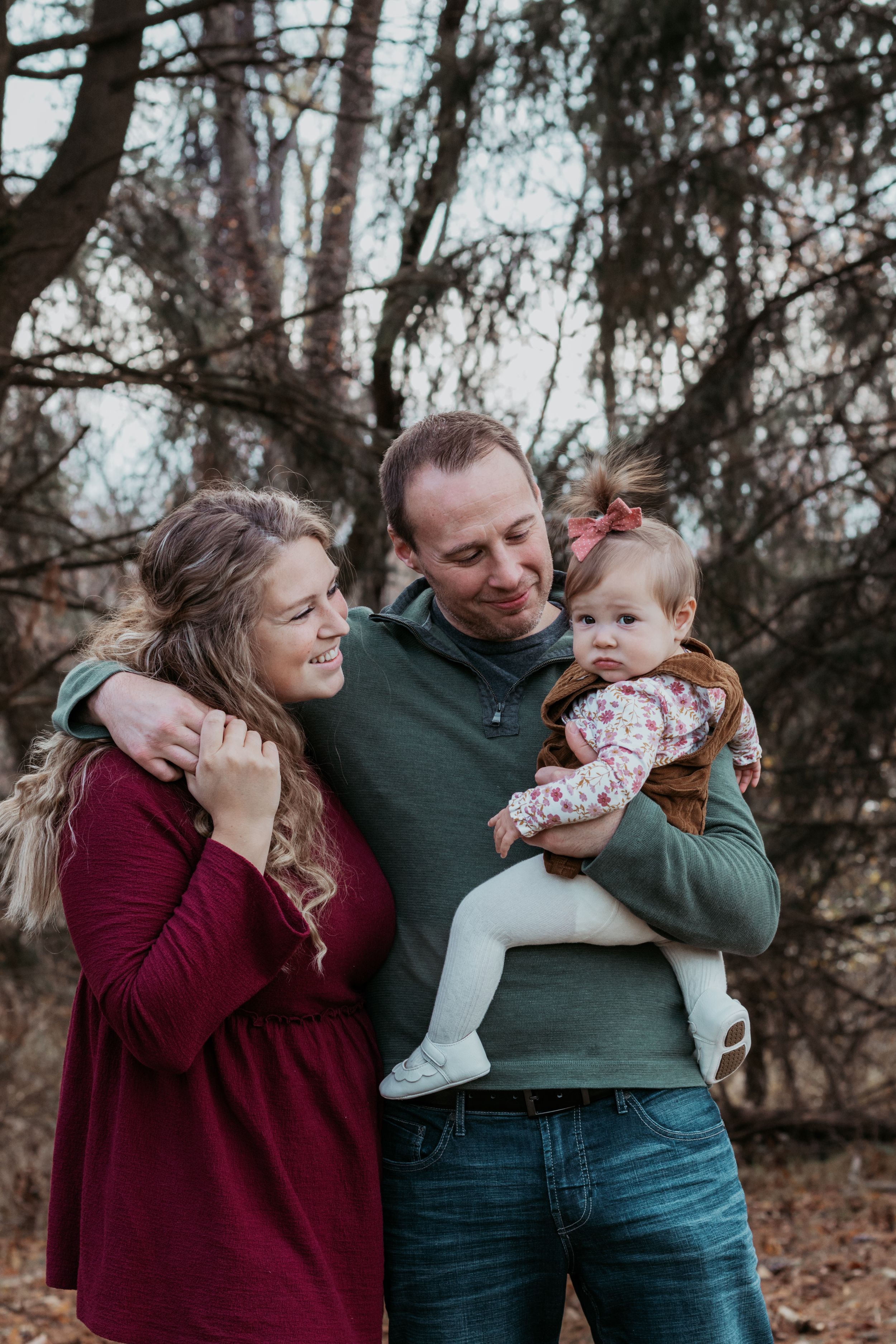Family sharing playful moments together in an autumn forest setting.
