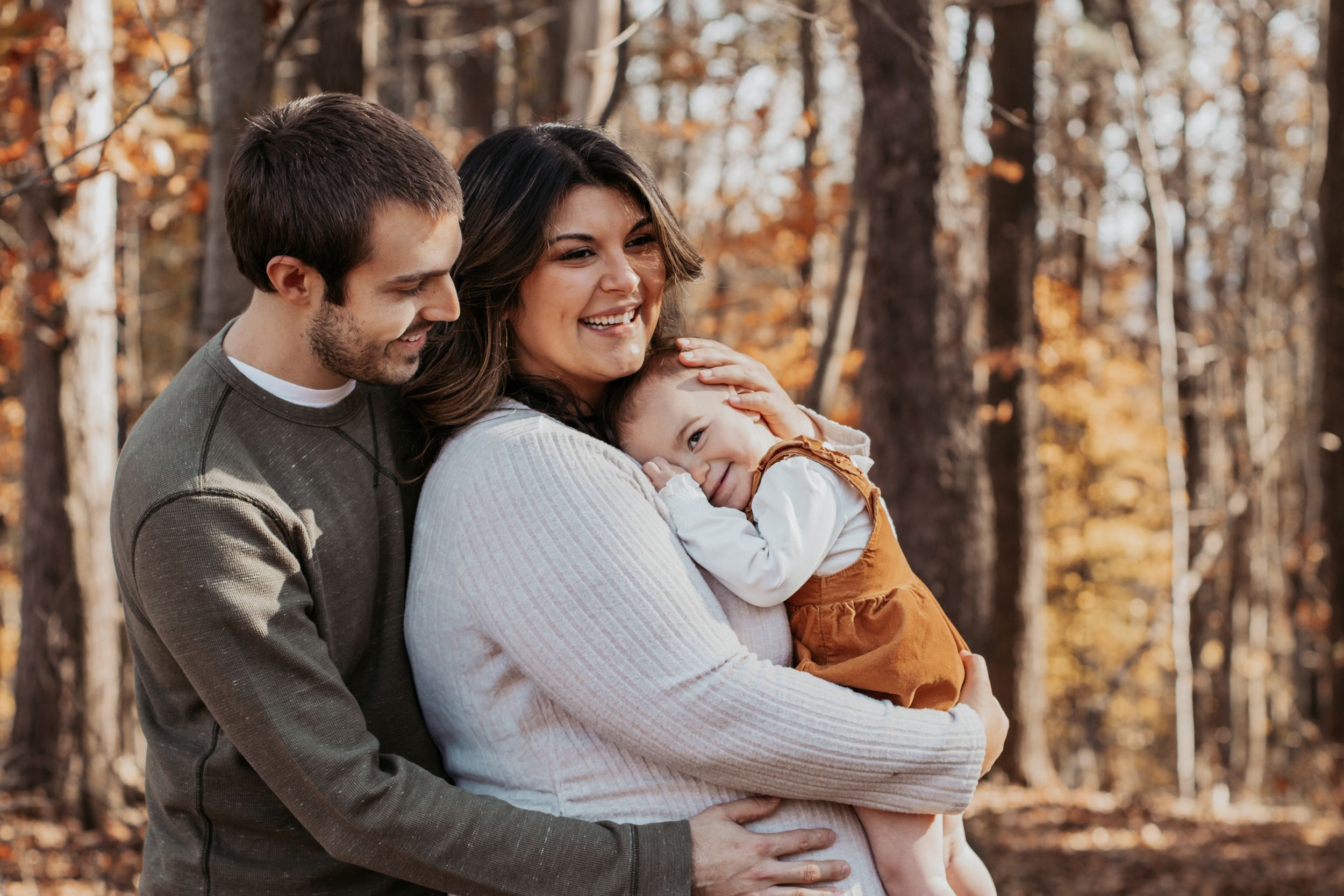 Happy family embracing and smiling together in autumn forest setting.