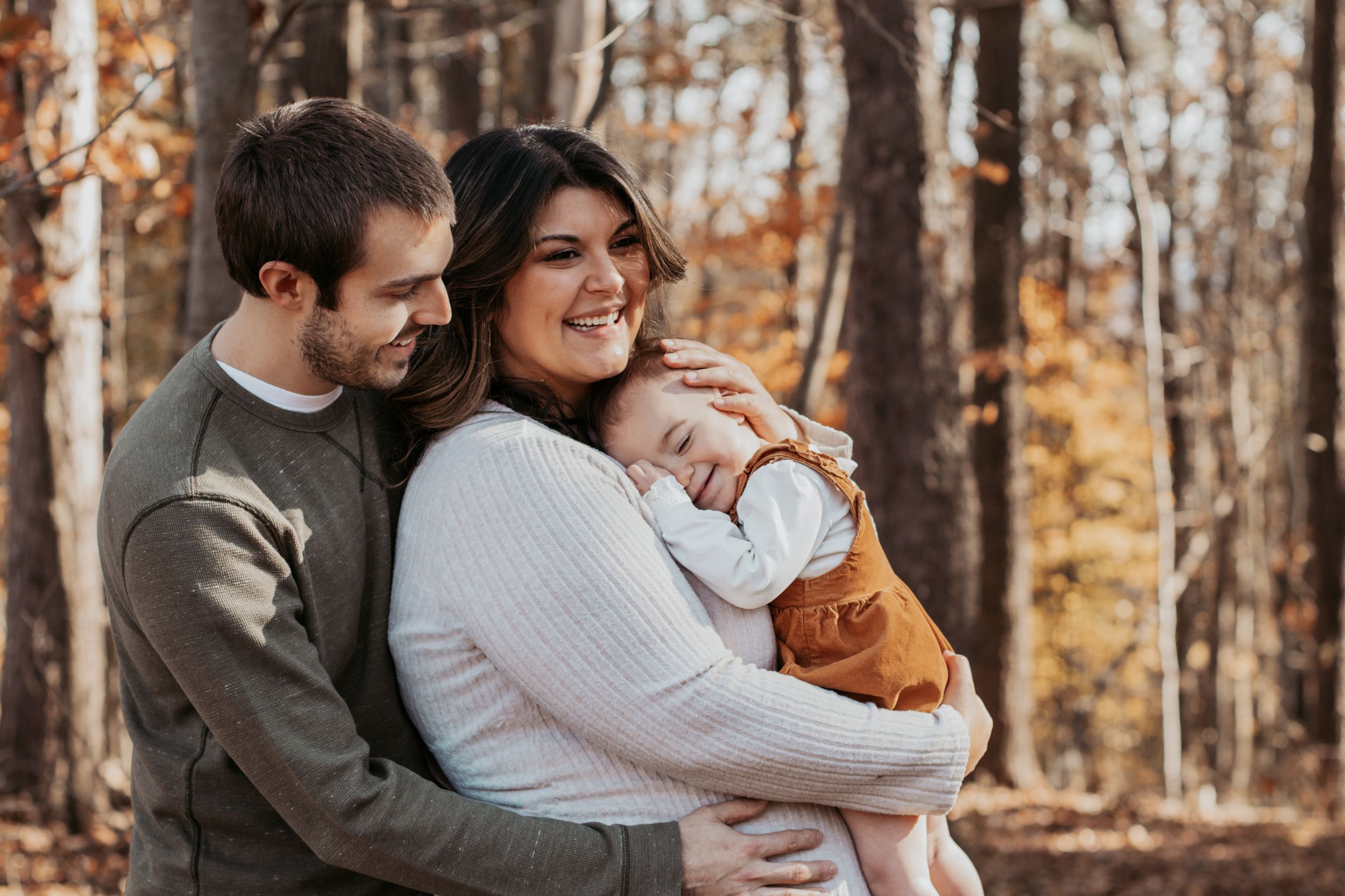 Candid family moments captured in warm autumn forest lighting.