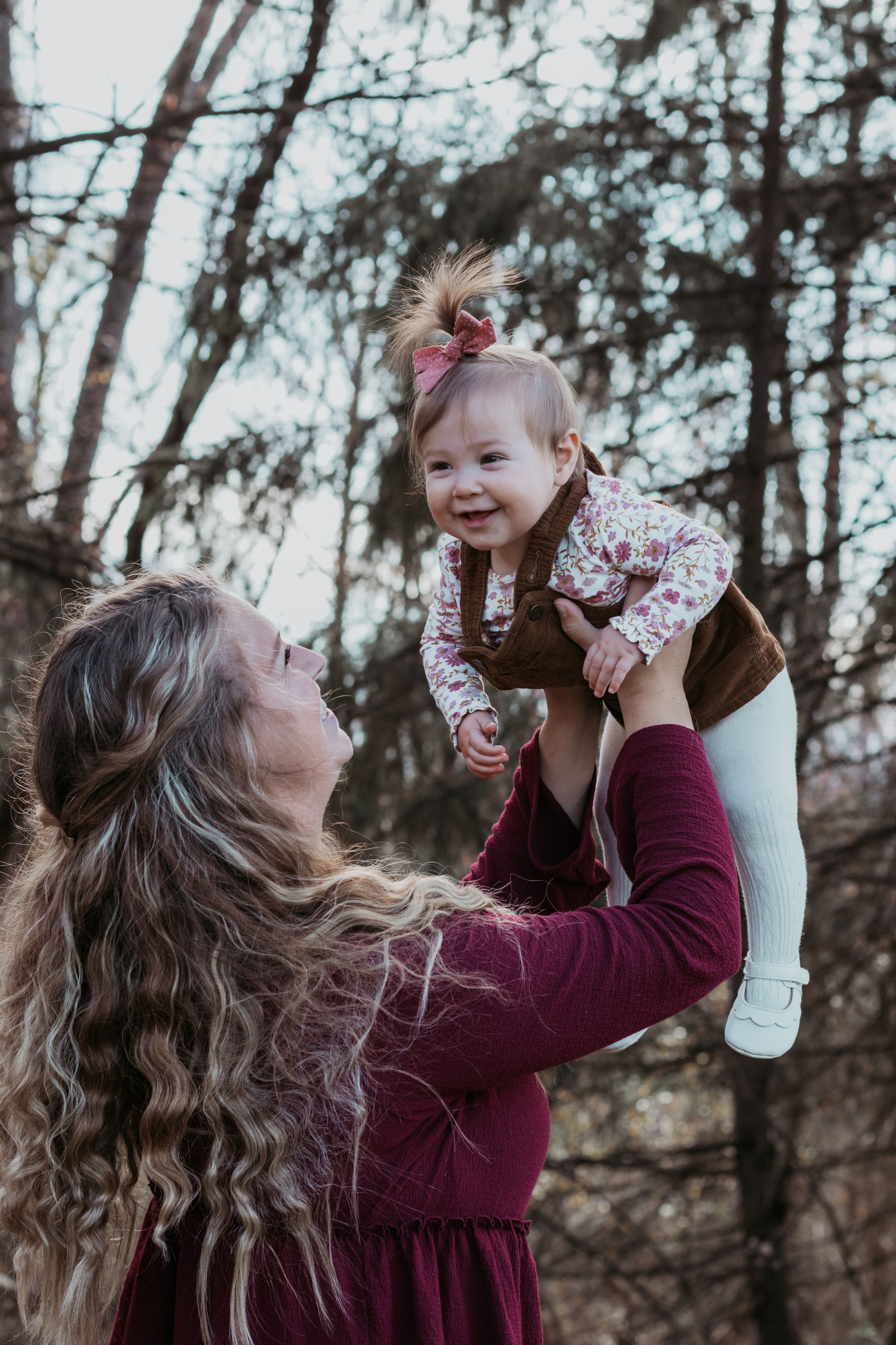 Playful moment between parent and baby outdoors among trees.