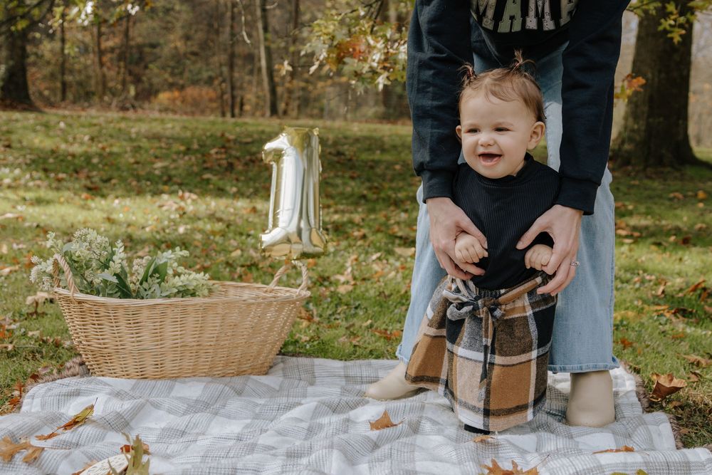 Happy child in black top and plaid pants enjoying outdoor autumn photo session.