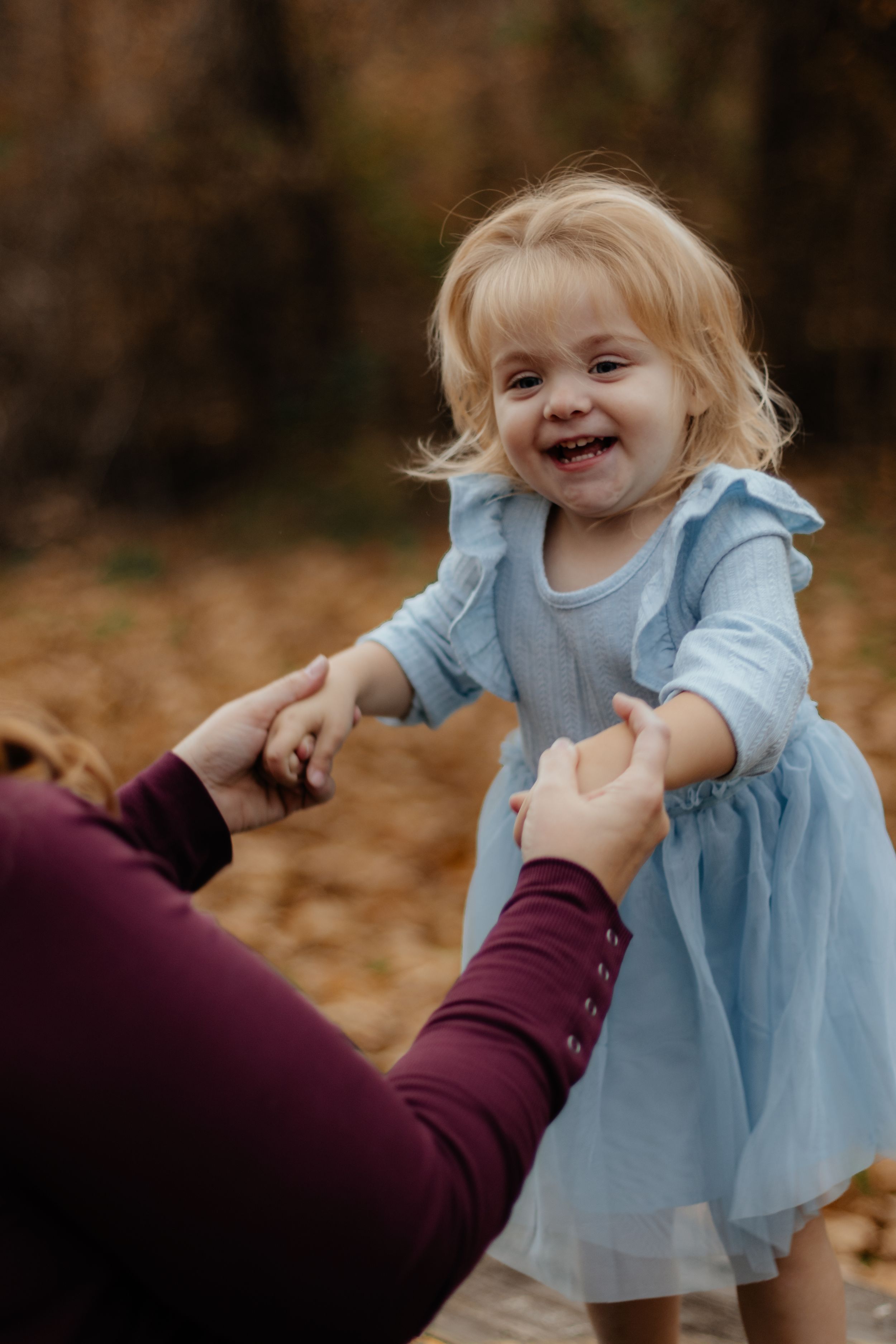 Playful moment captured as child in ruffled blue dress interacts with someone off camera.