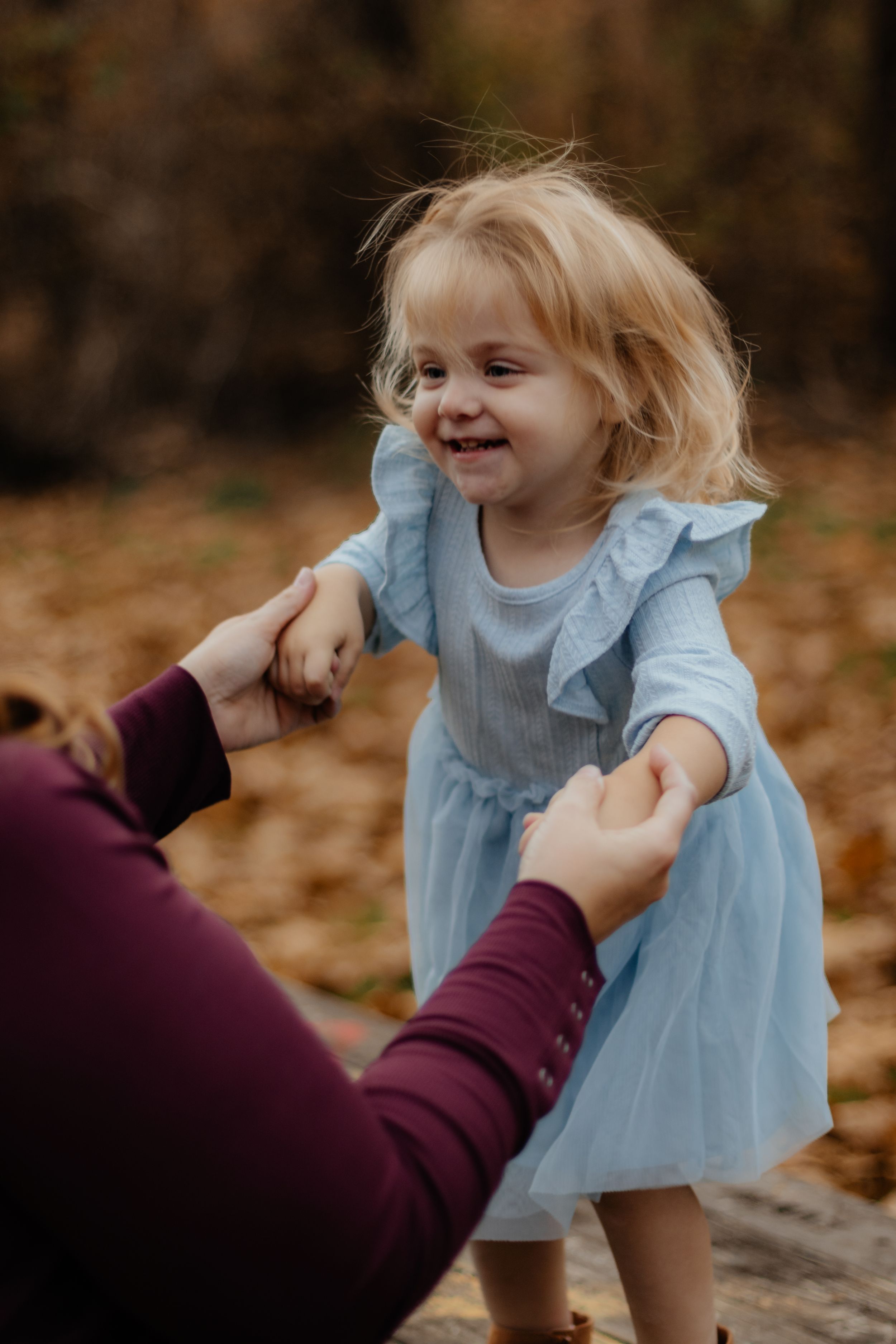 Candid sequence shows child laughing while wearing light blue dress during fall photo session.