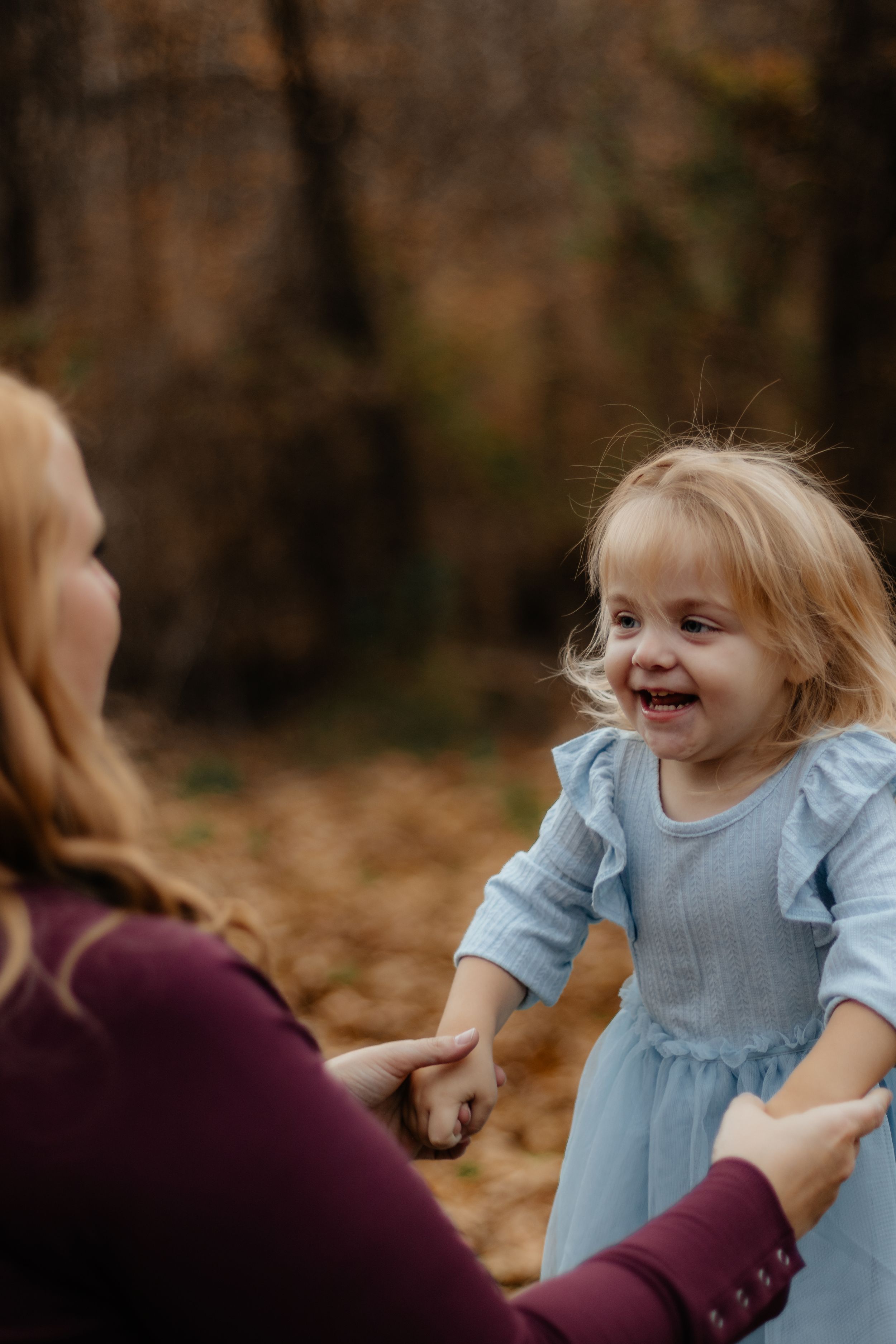 Sweet candid moments captured of child in blue dress playing during autumn photoshoot.