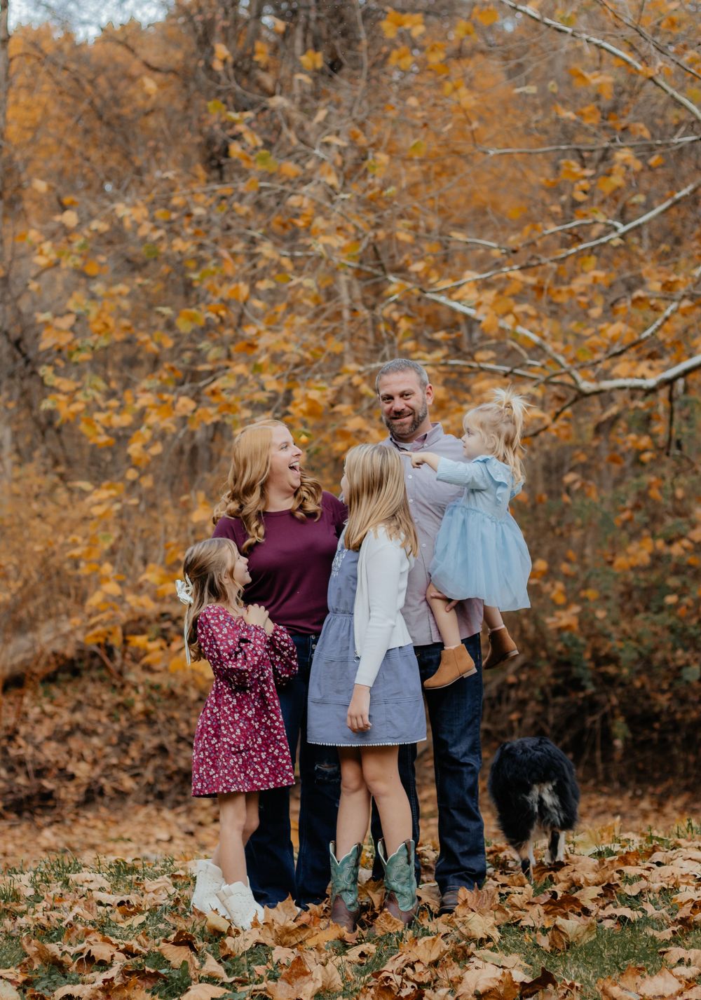 Candid family moment captured during fall photoshoot in woods.
