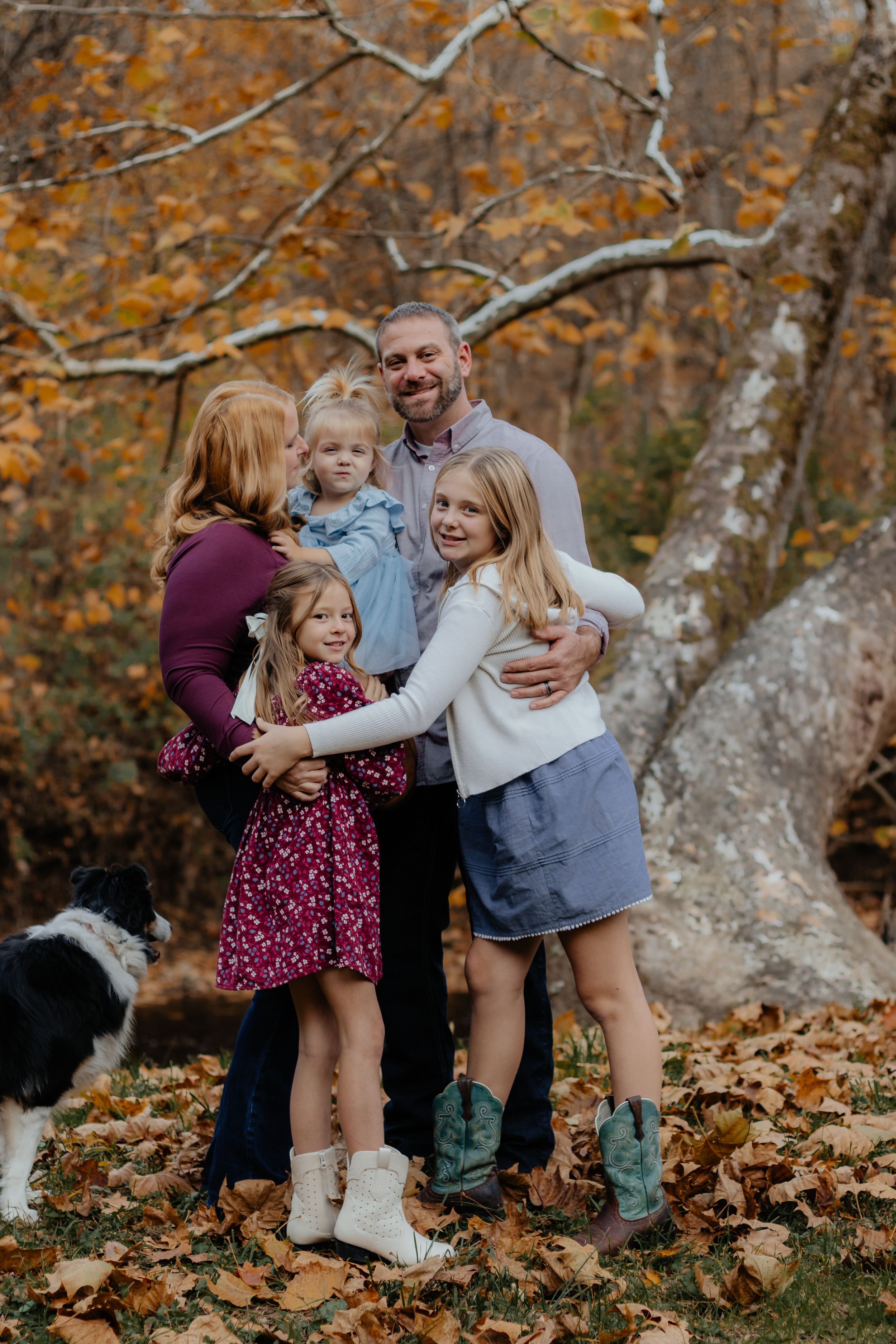 Playful family photo session with everyone laughing among autumn leaves.