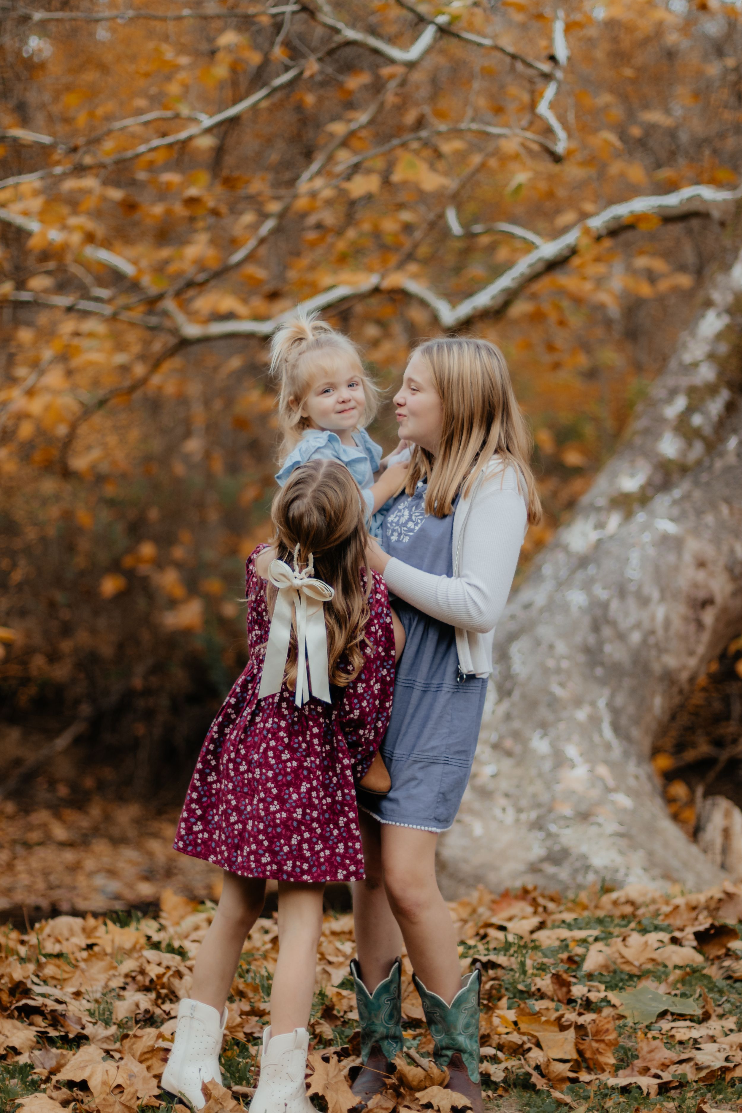 Children play and laugh together among fallen autumn leaves.
