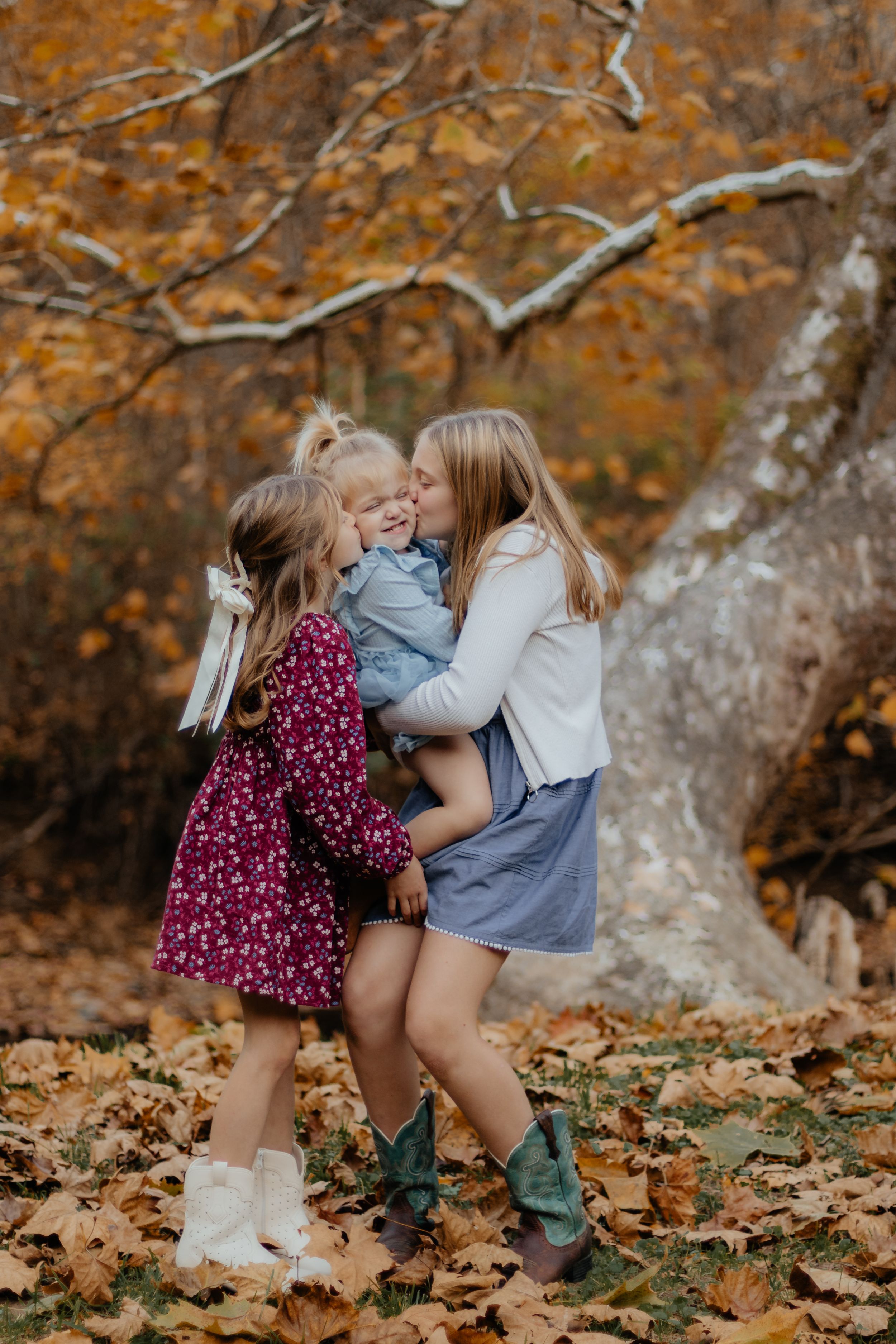 Children share laughter while playing in colorful autumn leaves.