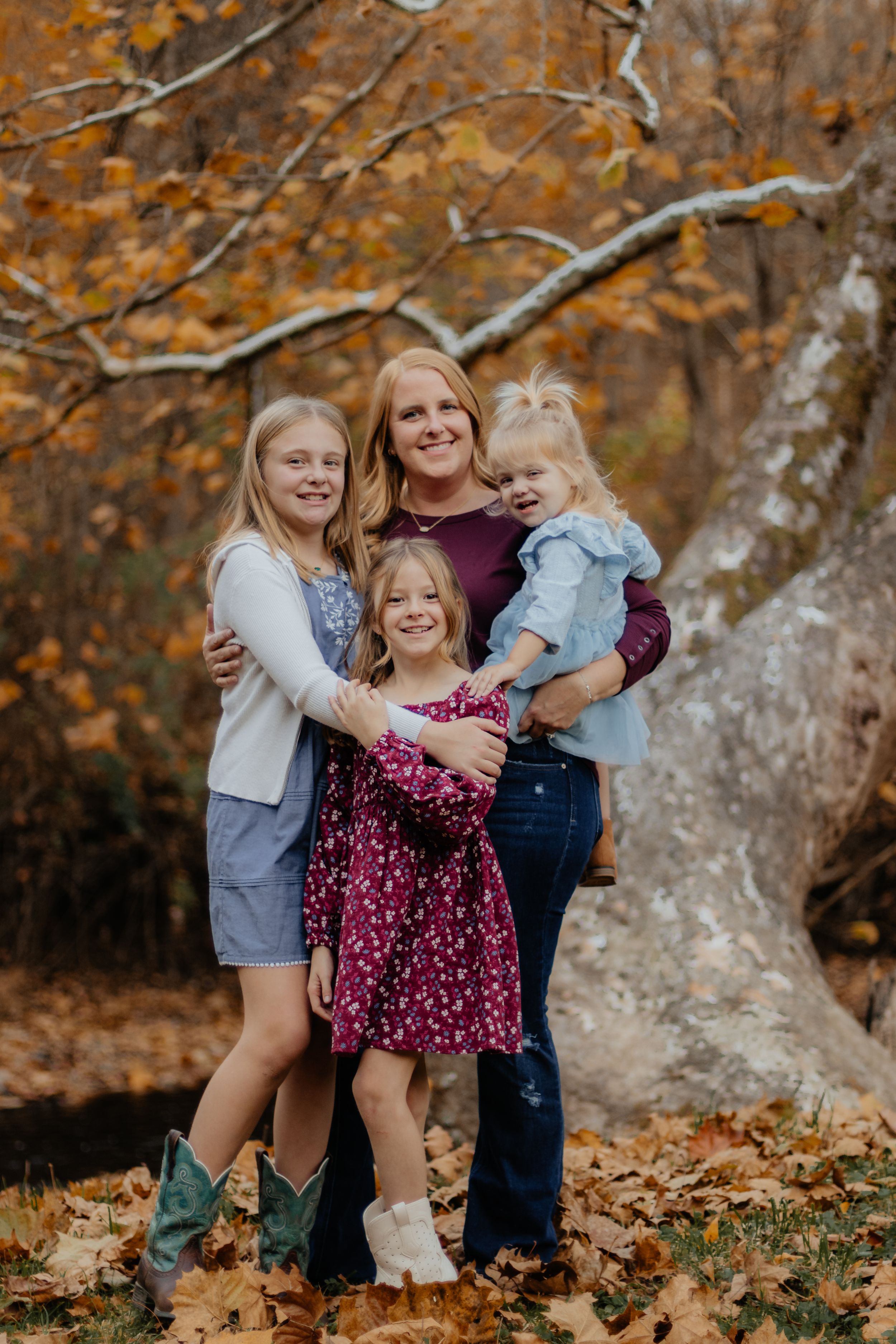 A group poses together against a backdrop of fall colors and a large tree trunk.