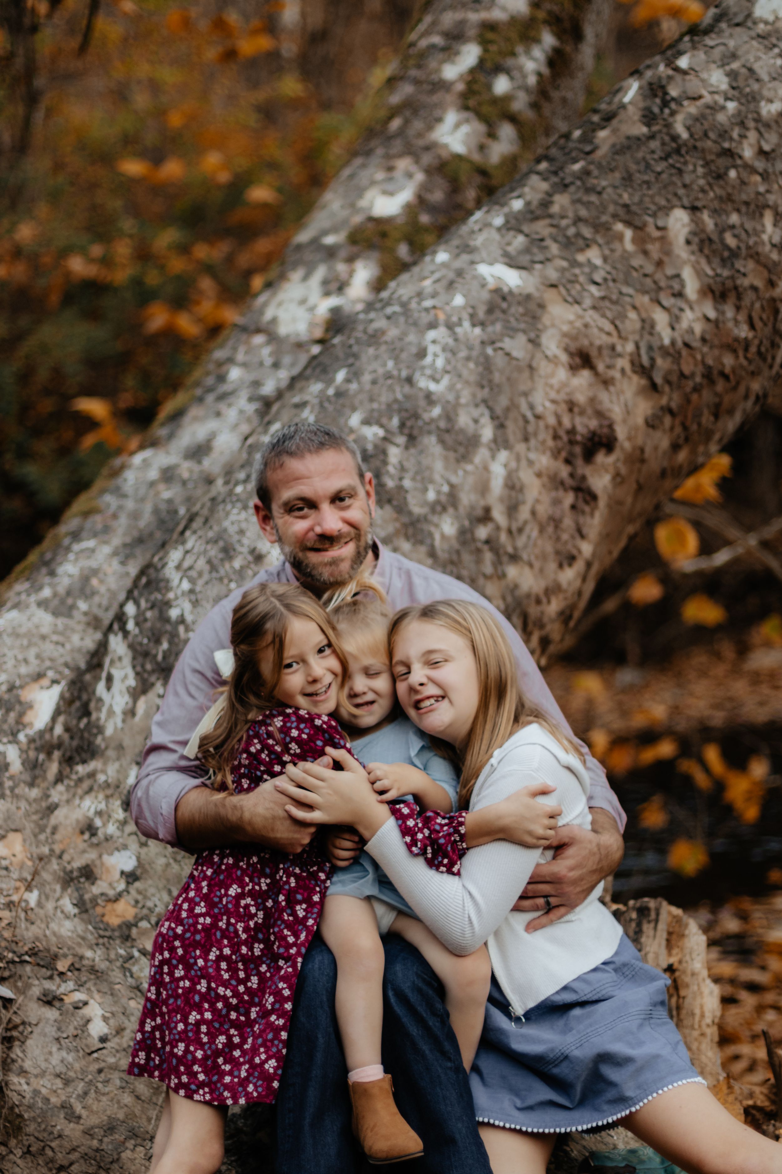 A group shares a tight embrace while sitting on a large rock formation.