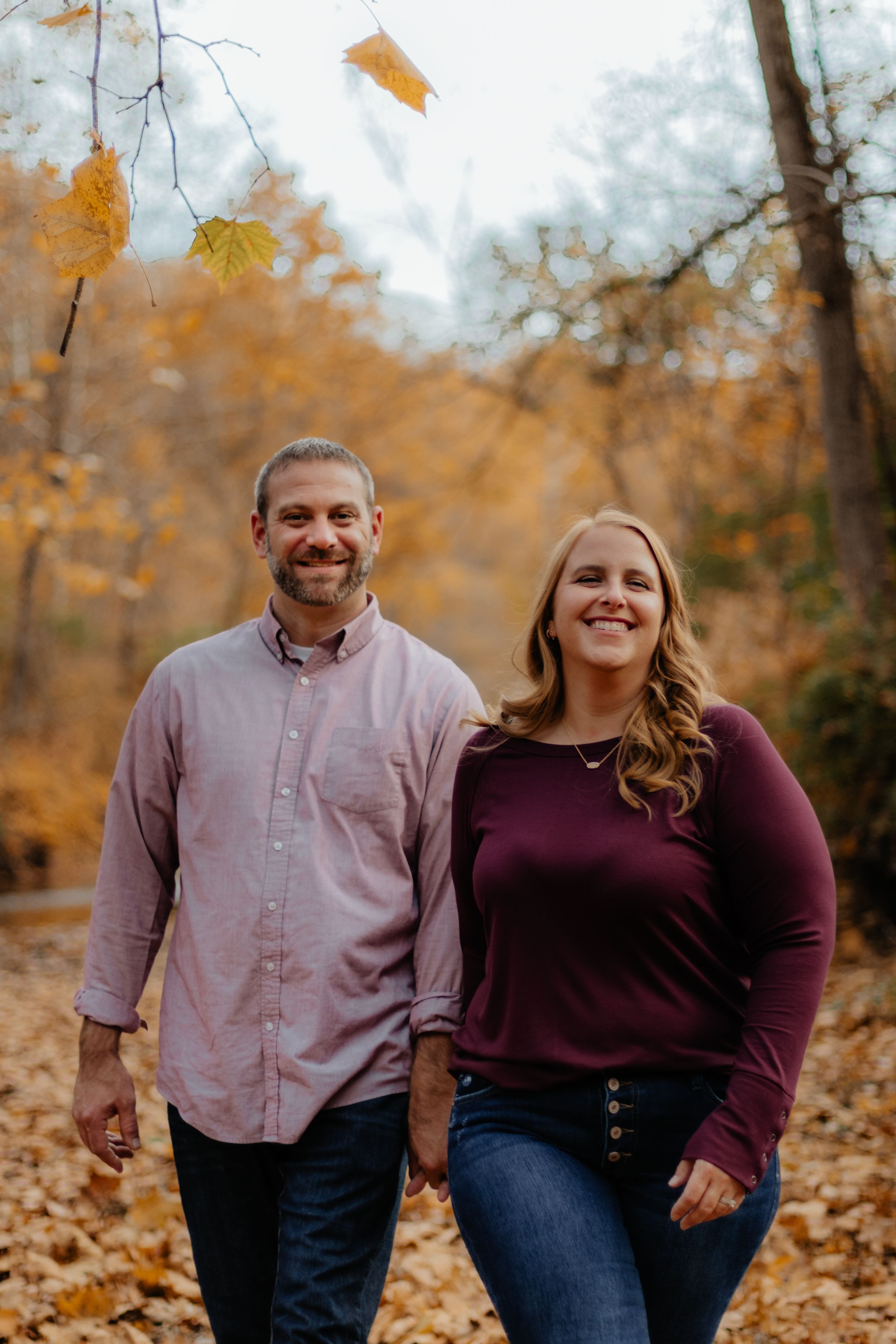 Happy couple walking and laughing together in autumn forest setting.
