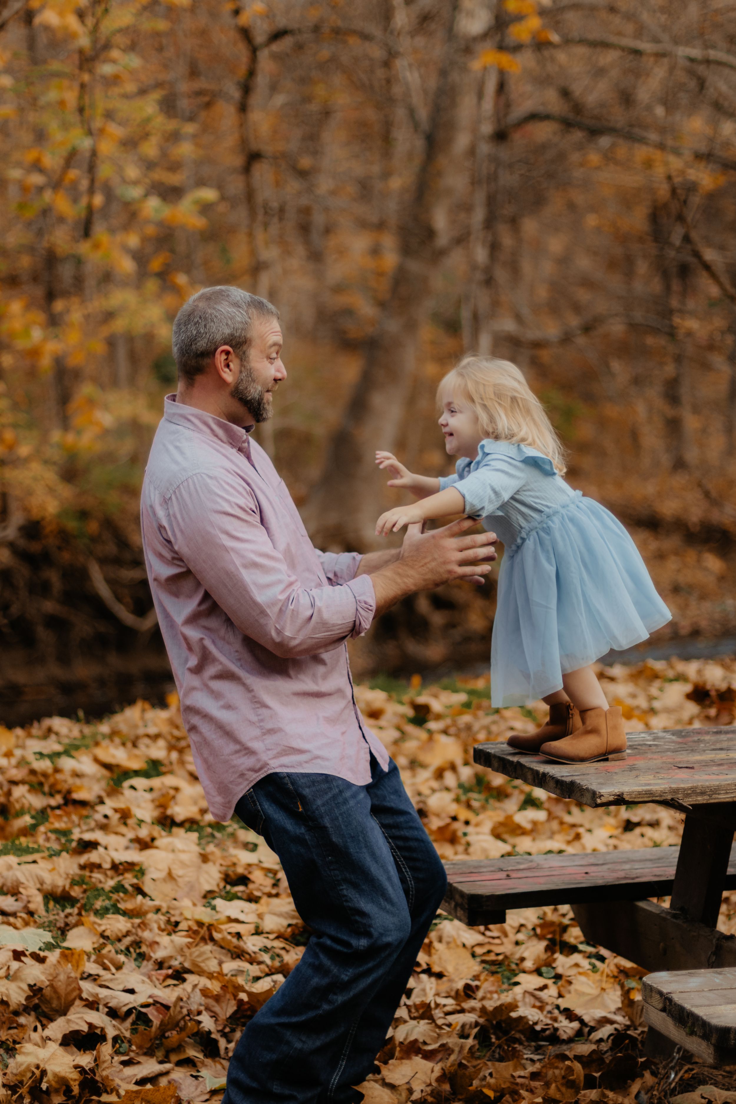 Playful moment captured during fall family photoshoot with autumn leaves scattered on ground.