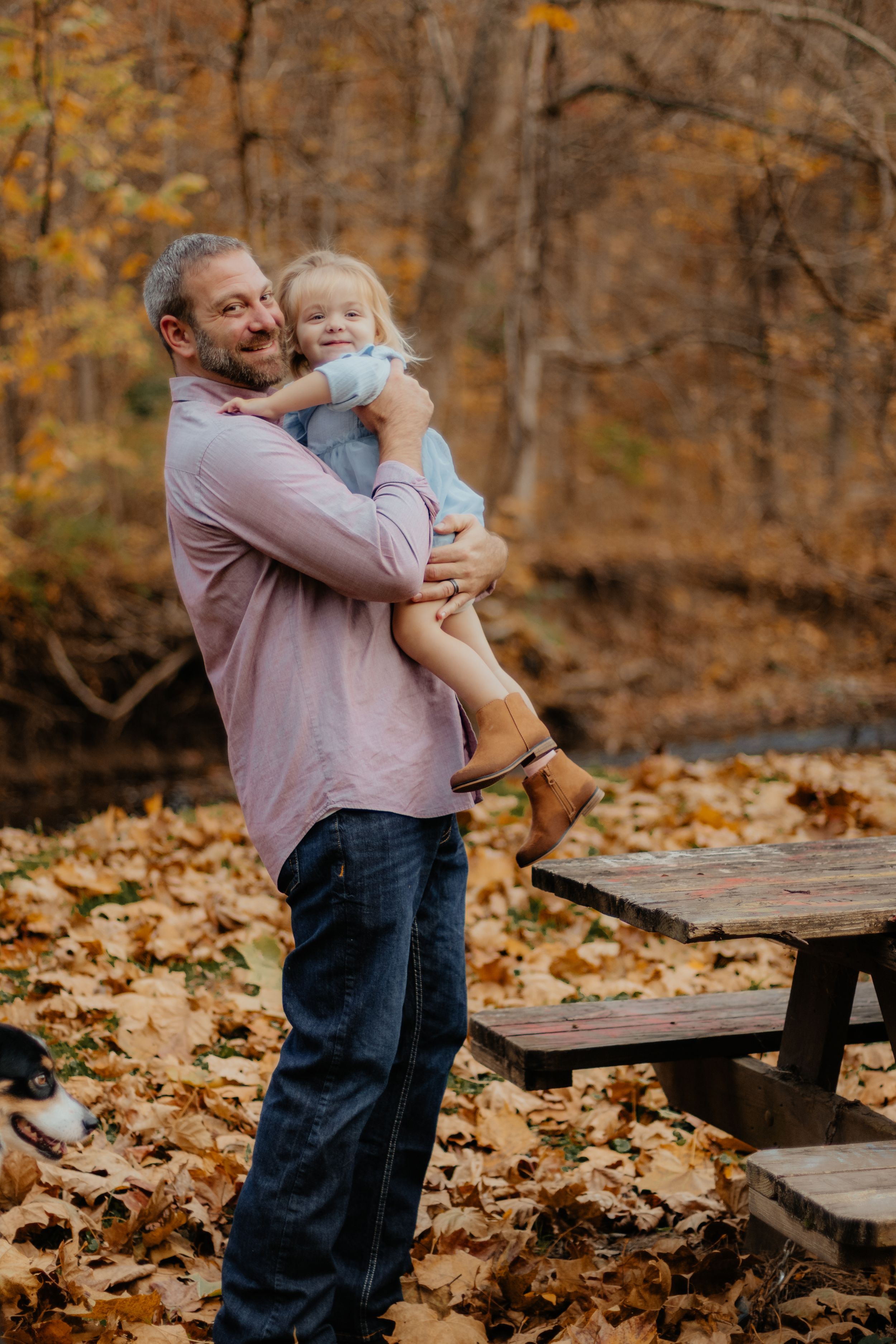 Heartwarming family moment captured during fall photoshoot in wooded setting.
