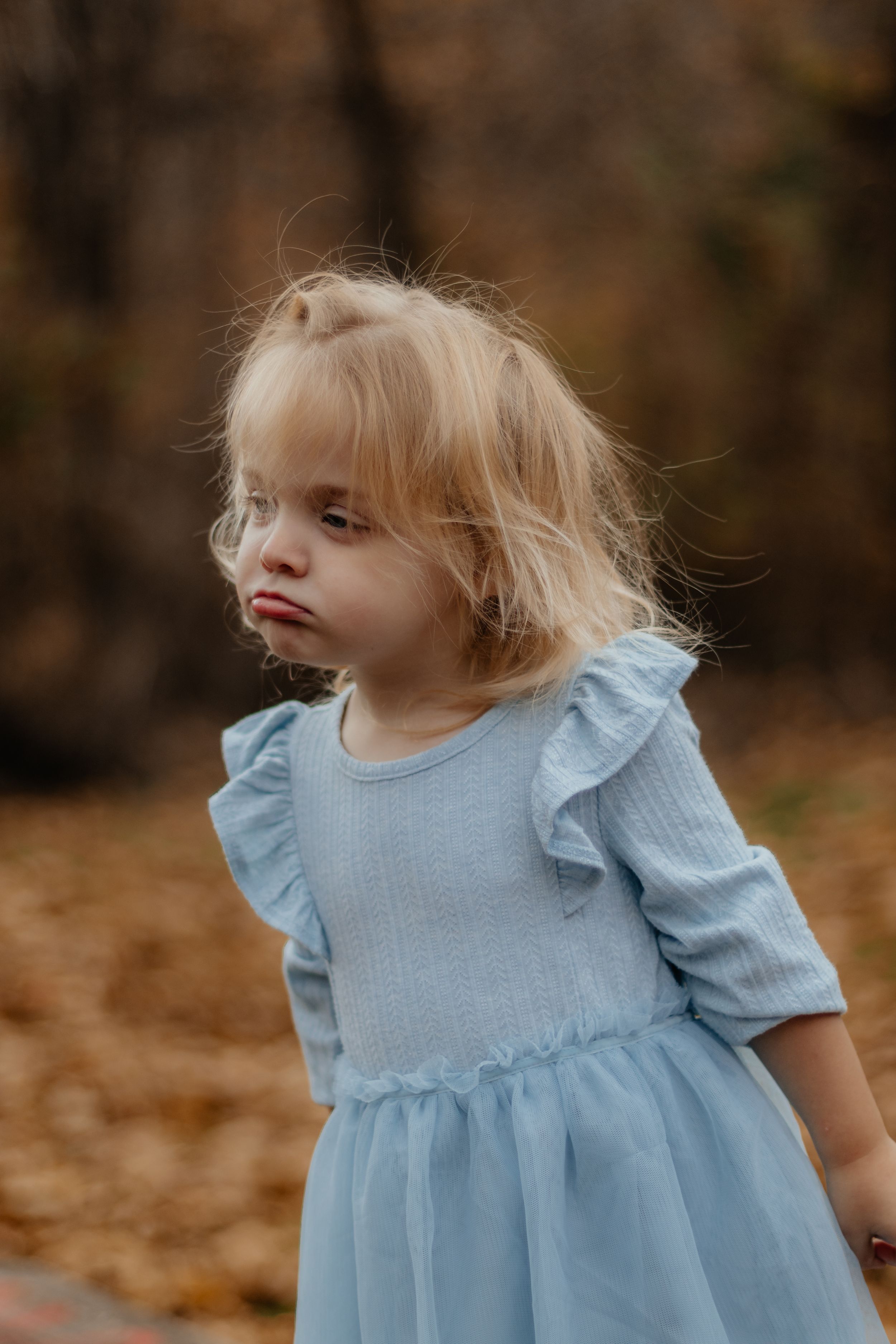 Child wearing a light blue ruffled dress during an autumn photoshoot.