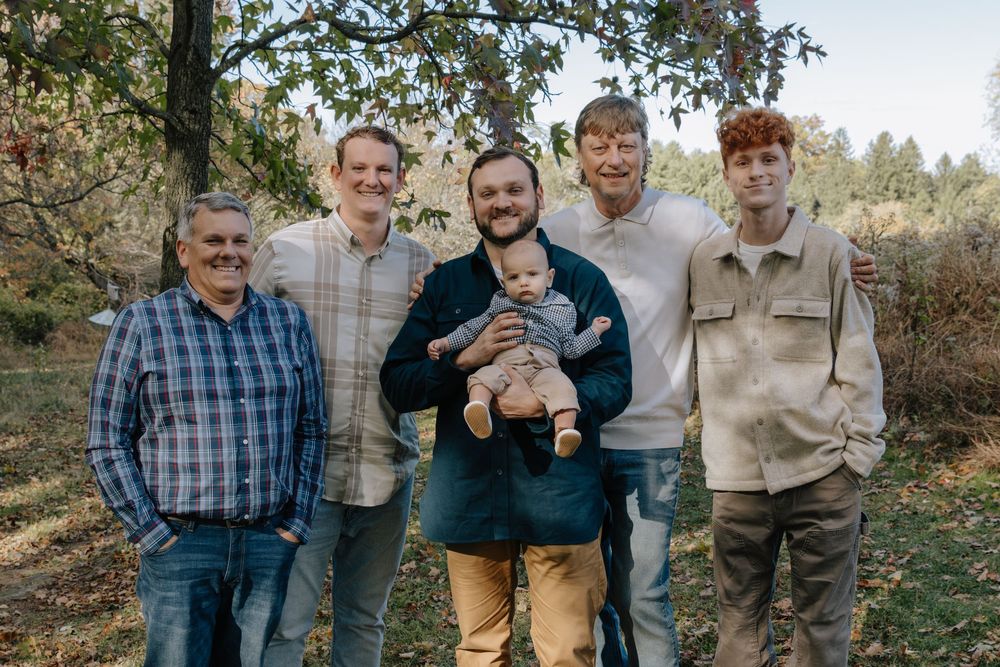 Group photo of family members standing together in wooded area.