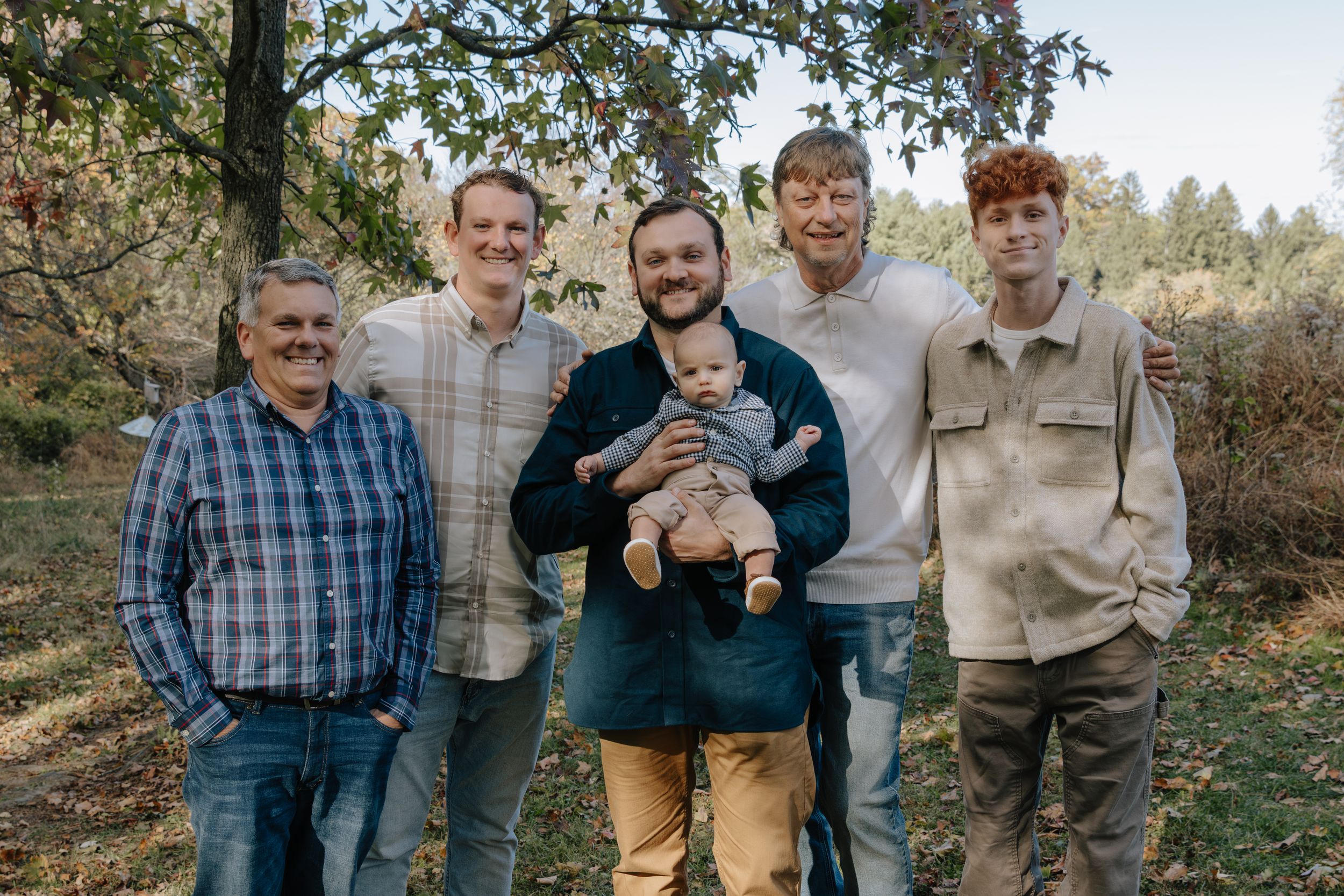Group photo of family members standing together in wooded area.