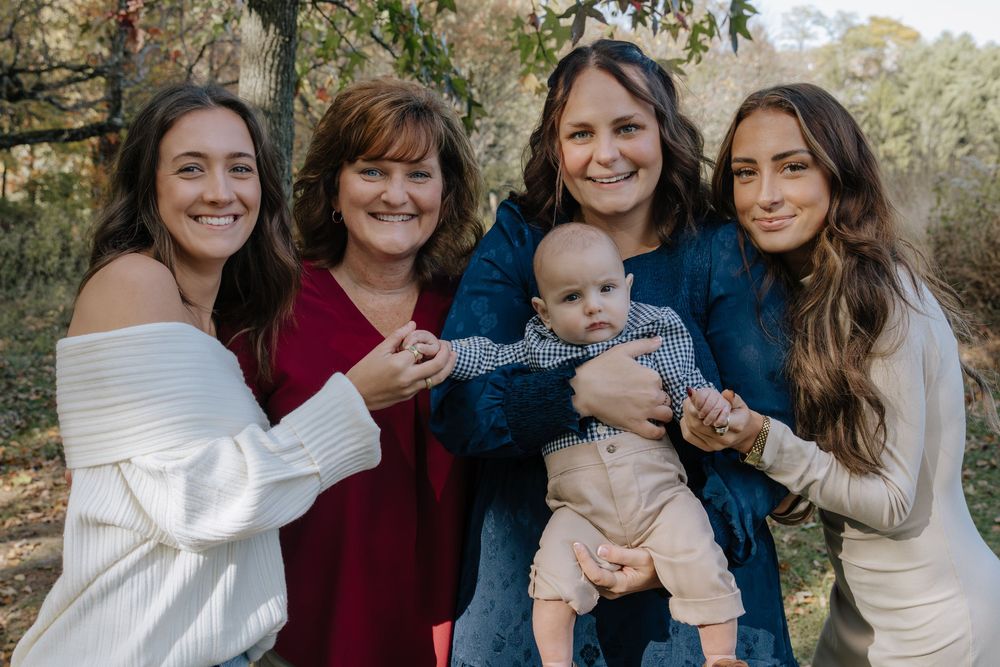 Family members gather for outdoor portrait session in autumn setting.