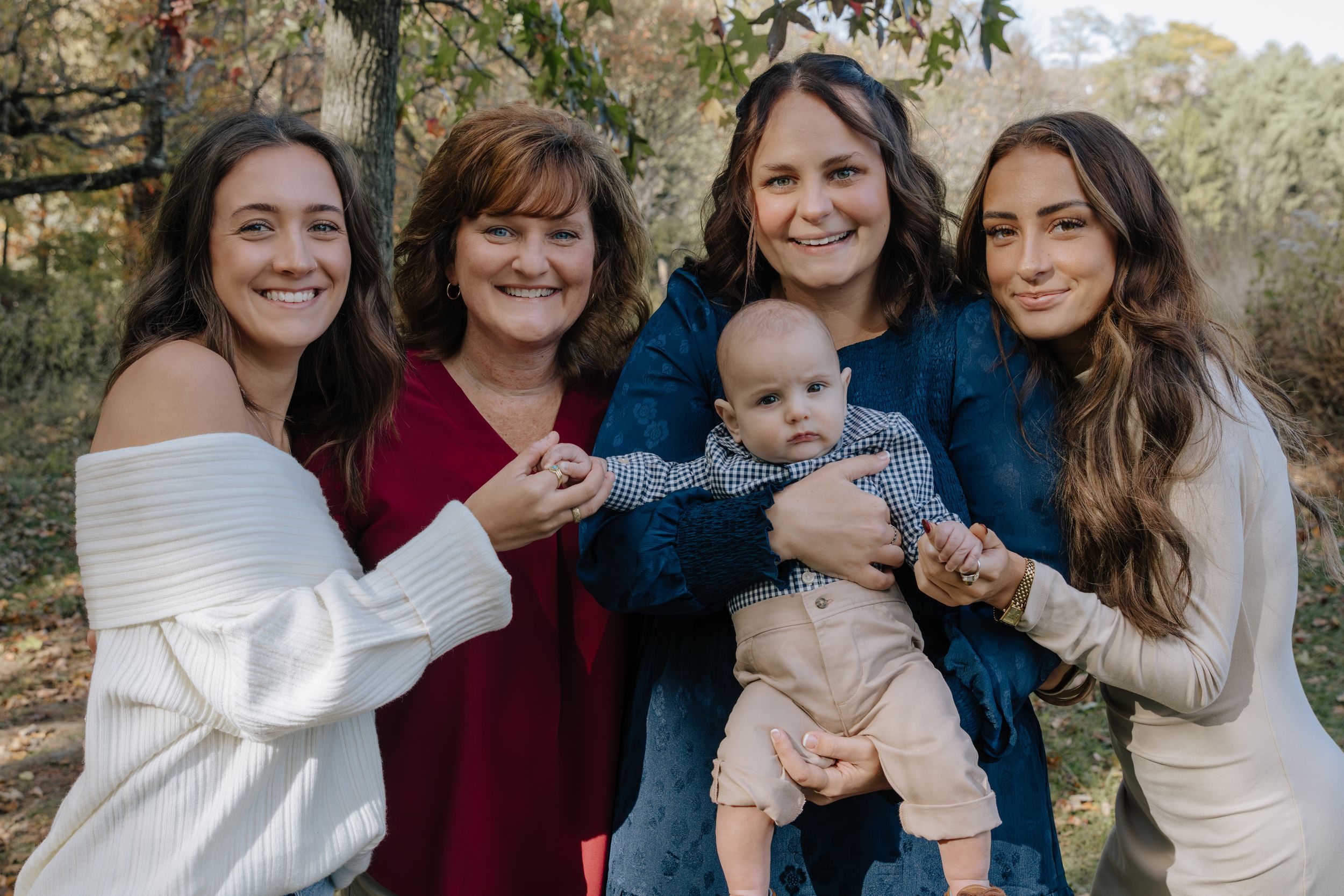 Family members gather for outdoor portrait session in autumn setting.