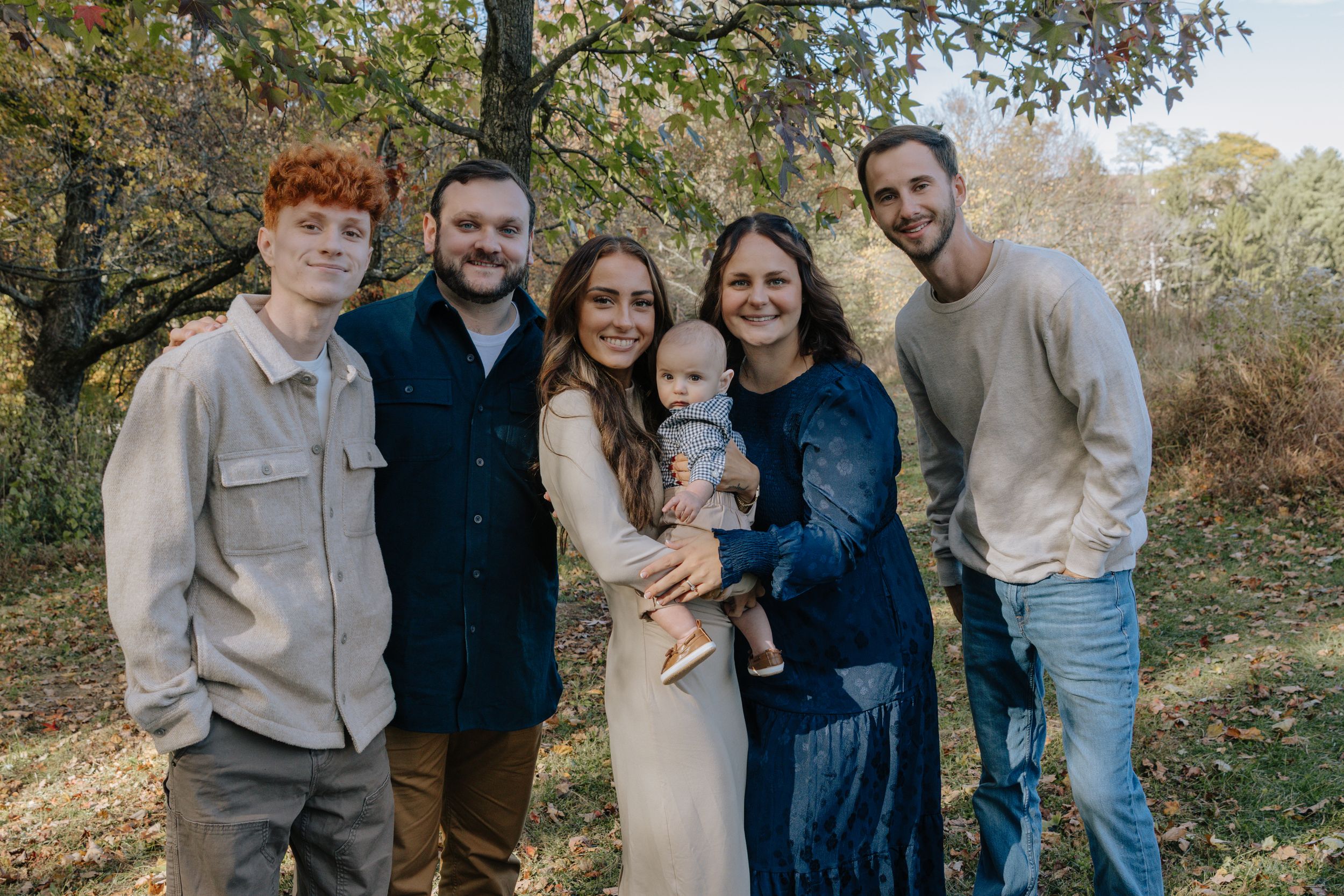 Multiple generations pose for casual outdoor family photos in coordinated blue and neutral clothing.
