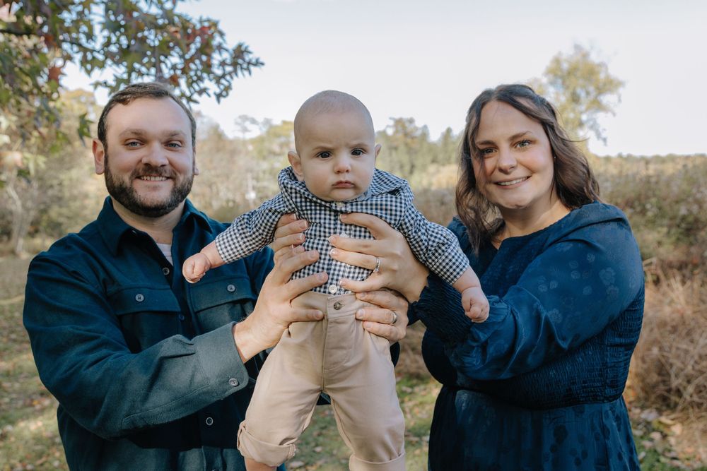 Outdoor family photoshoot capturing playful moments between parents and baby.
