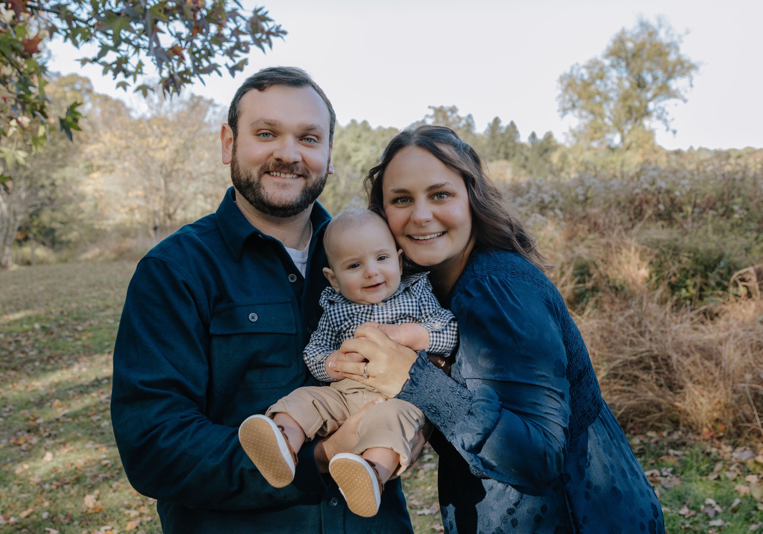 Natural light family portrait showing affectionate moments with their young child.