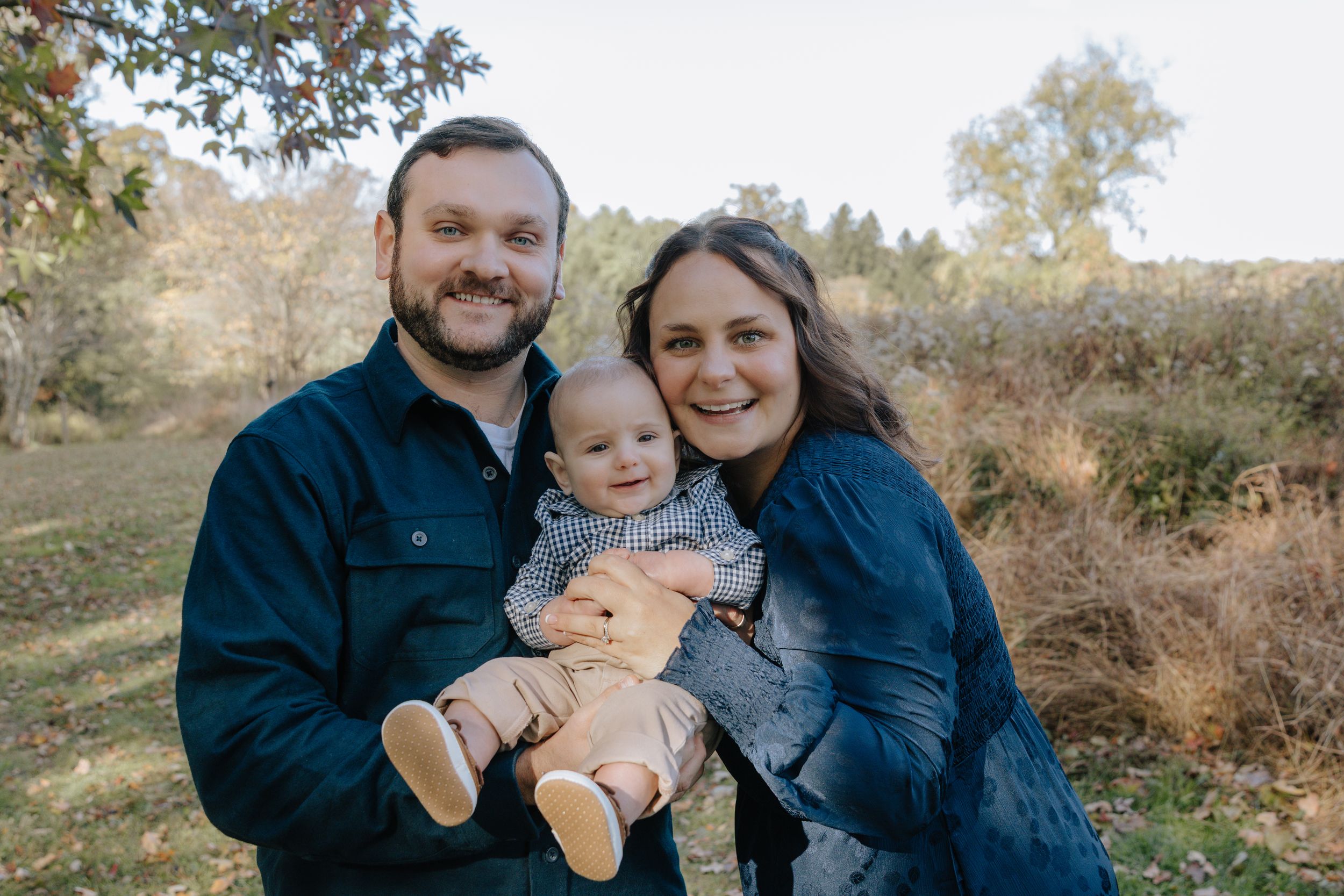Casual outdoor family photo session showing loving interactions with baby.