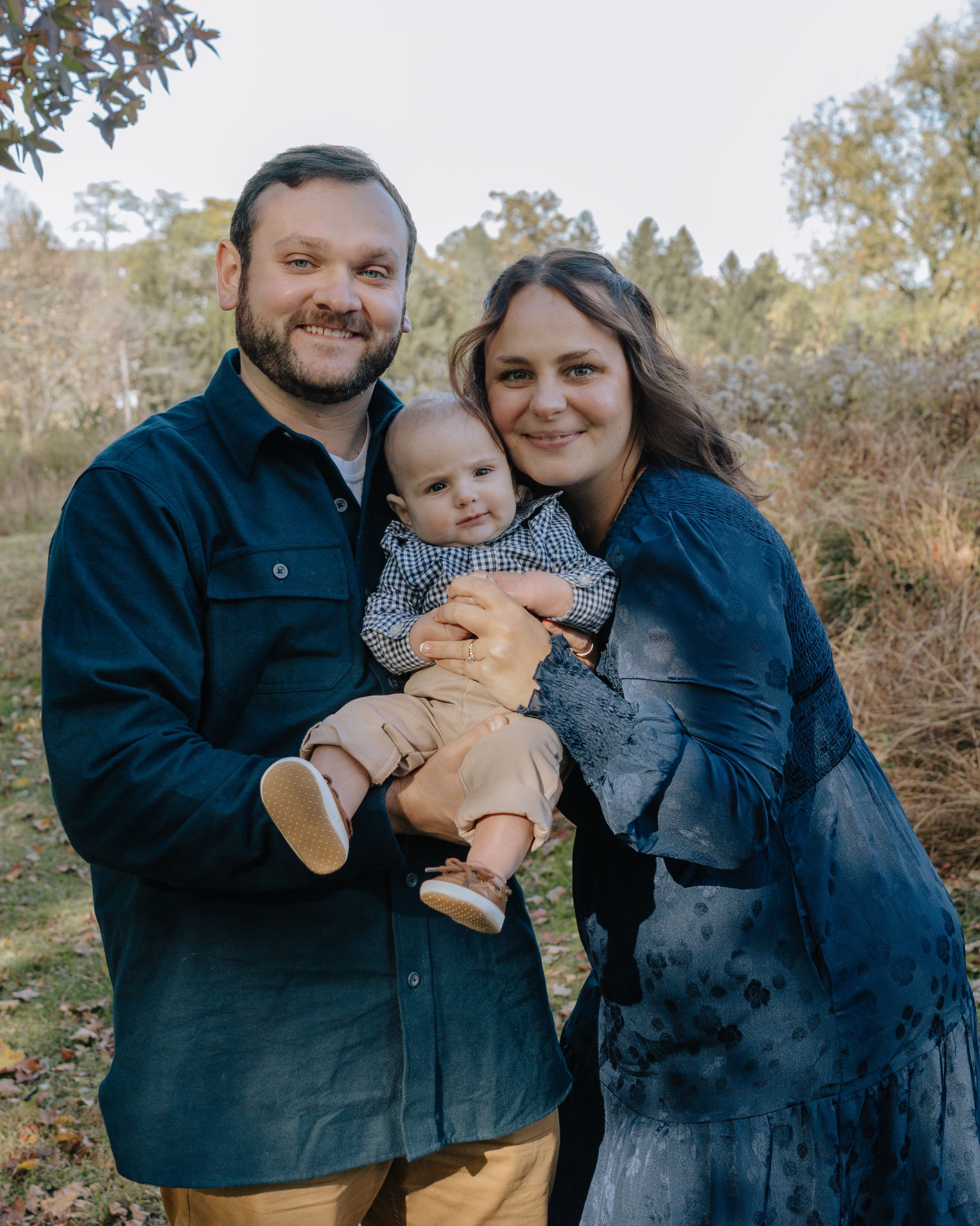Family dressed in dark clothing shares intimate moments during outdoor photoshoot.