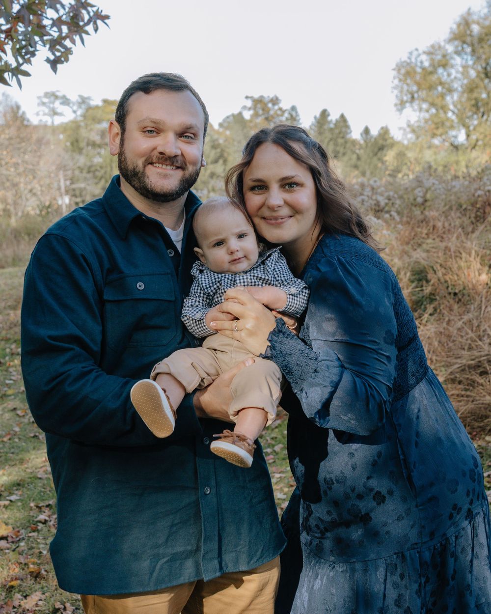 Family dressed in dark clothing shares intimate moments during outdoor photoshoot.