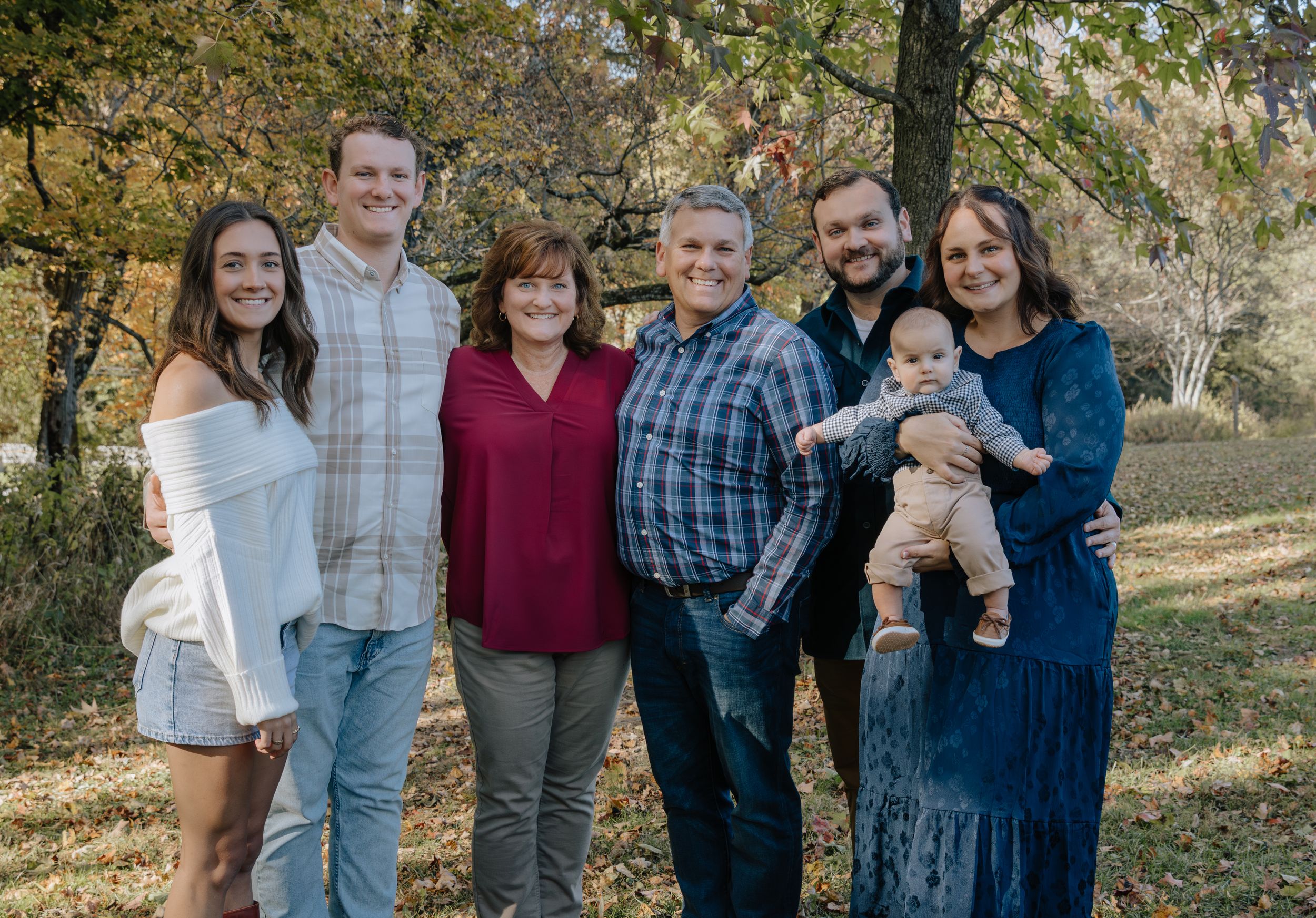 Extended family gathering captured in casual outdoor autumn setting.