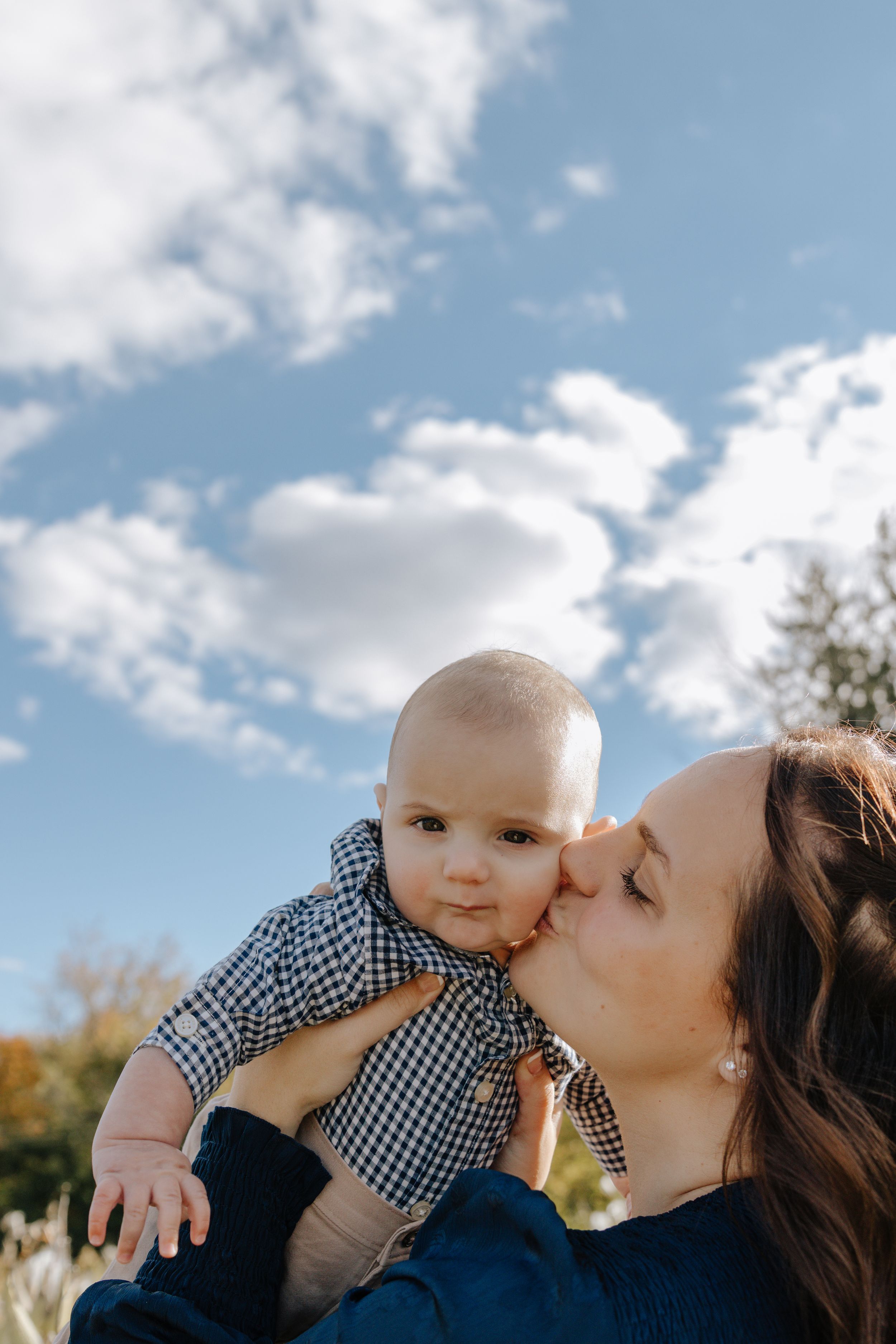 Sweet moment of affection shared between parent and infant outdoors on a sunny day.
