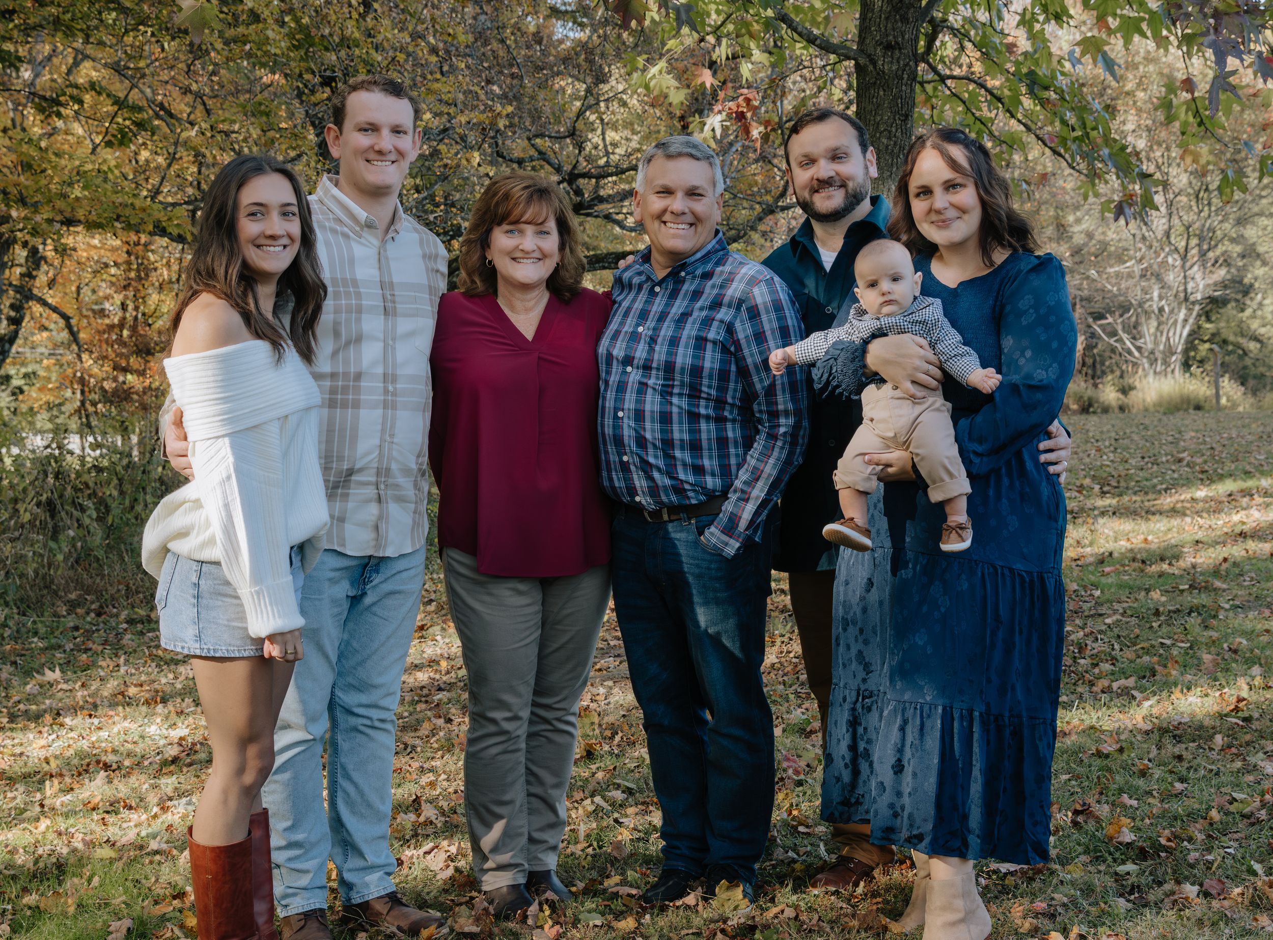 Extended family poses together outdoors on an autumn day in casual attire.