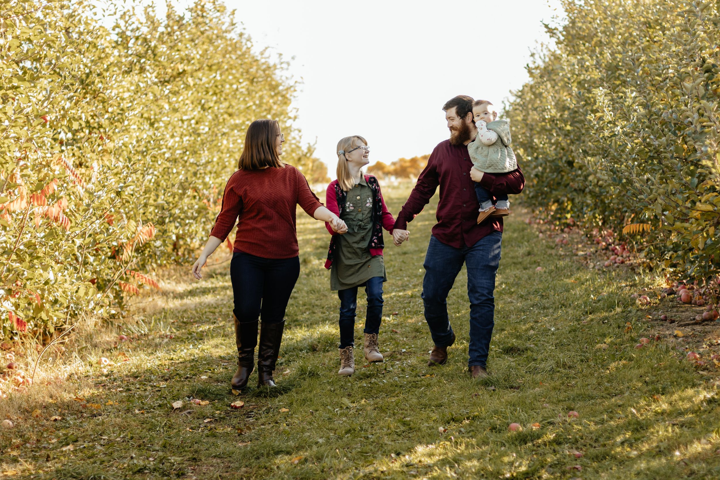A candid shot of a family walking together through a golden autumn field at sunset.