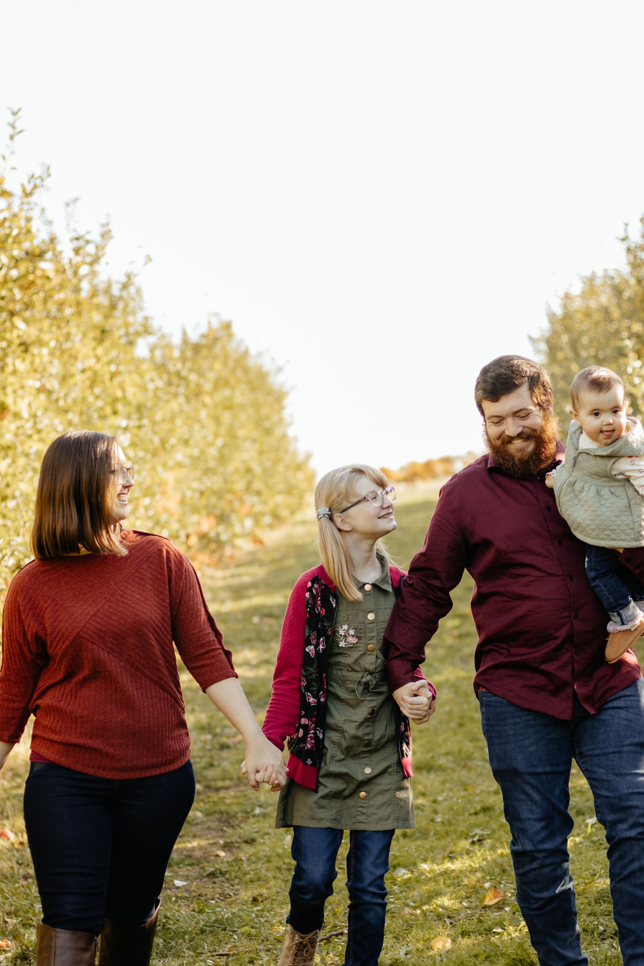 Family enjoying a playful autumn photoshoot outdoors with golden foliage in the background.