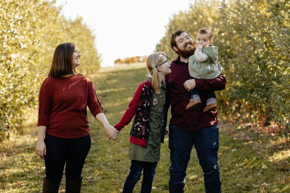 Casual outdoor family photography session with fall foliage creating a golden backdrop.