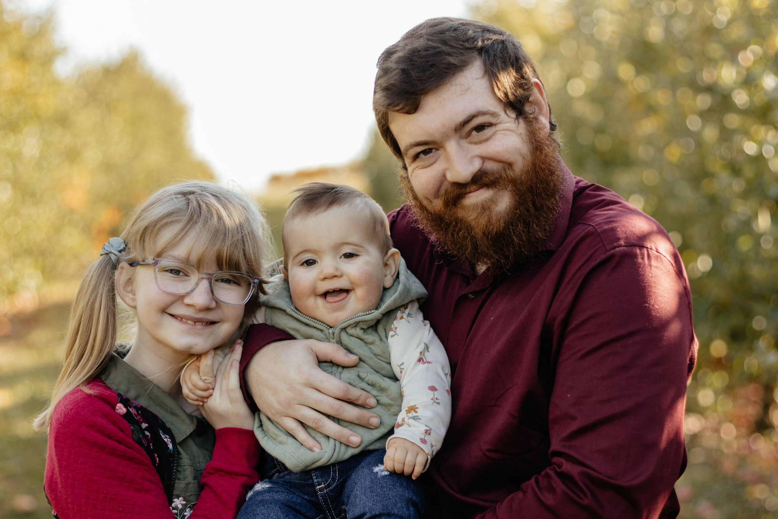 Candid family interactions during fall photo session with golden leaves in background.