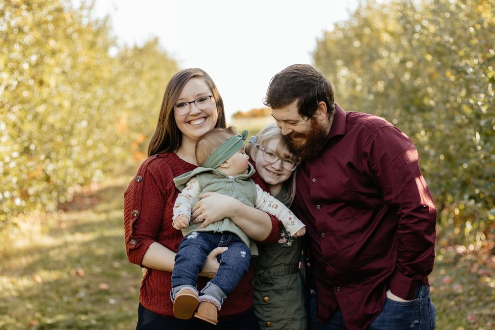 Natural family portrait session with golden autumn trees and warm-toned outfits.