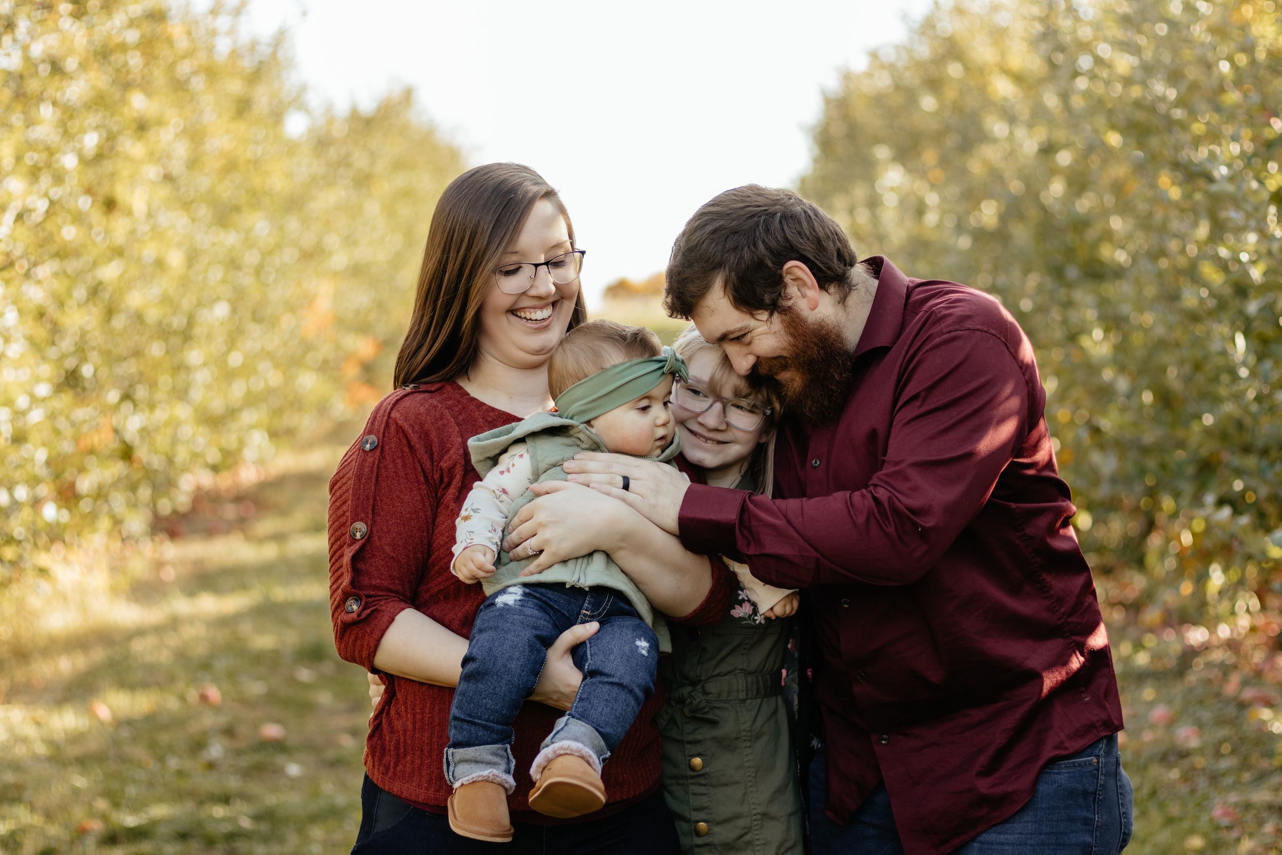 Joyful family photo session against backdrop of autumn trees and golden light.