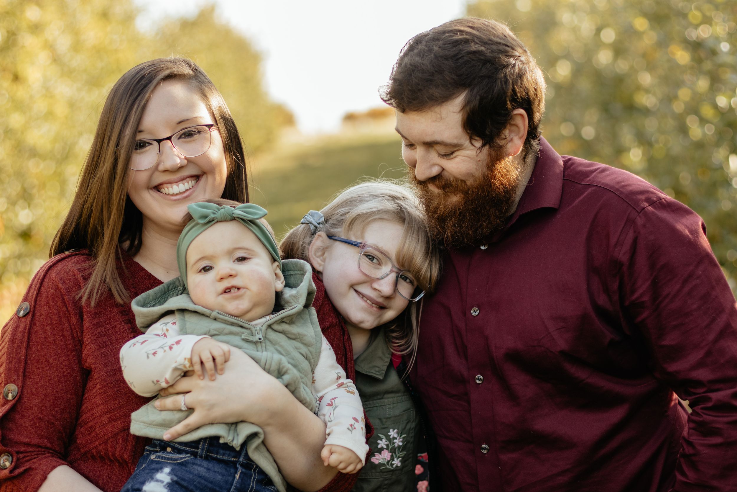 A family shares a tender moment together while sitting on grass during a fall photo session.