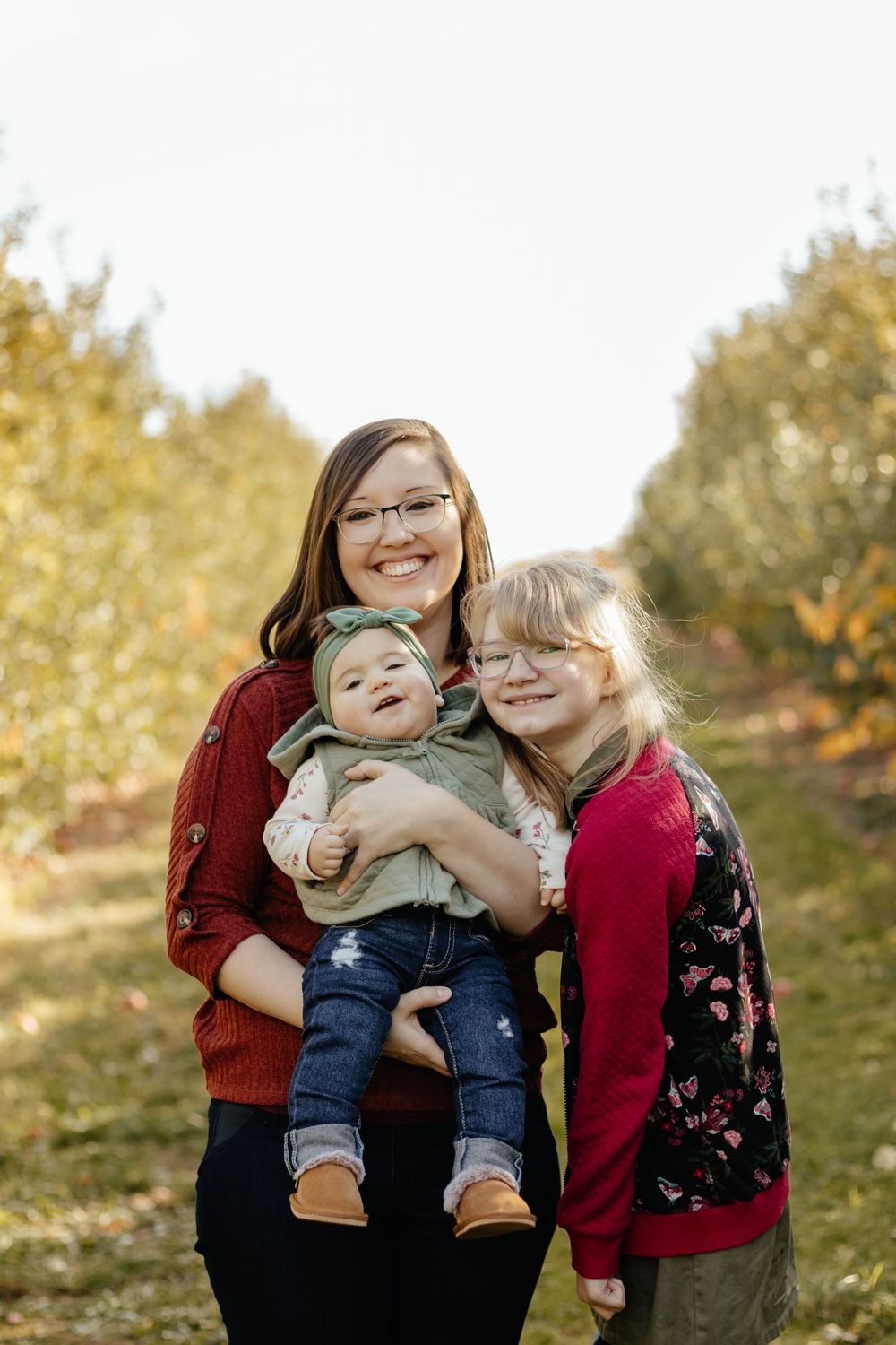 Three people share joyful hugs and laughter during an outdoor autumn portrait session.