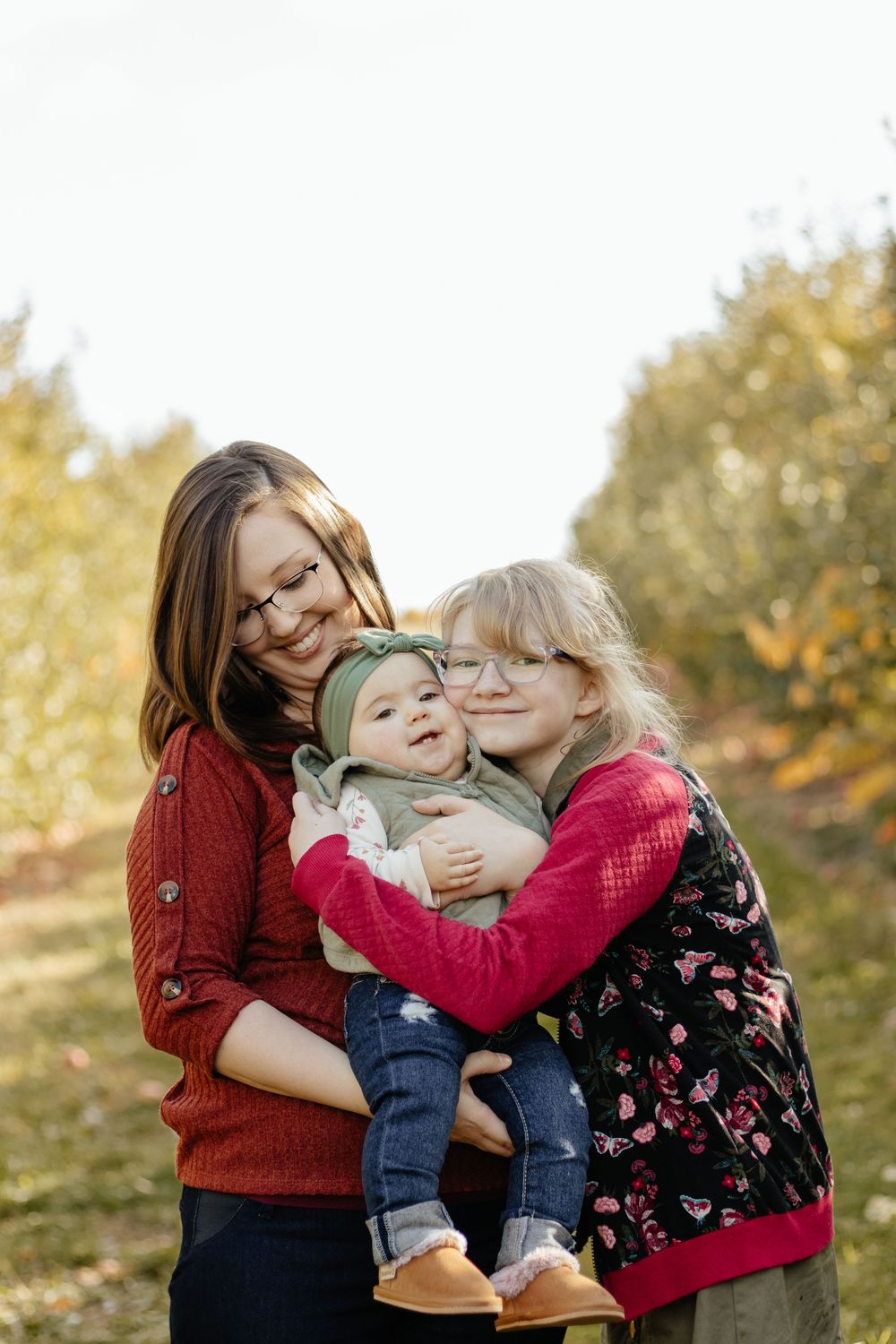 Candid moment of family members hugging and laughing together in an autumn setting.