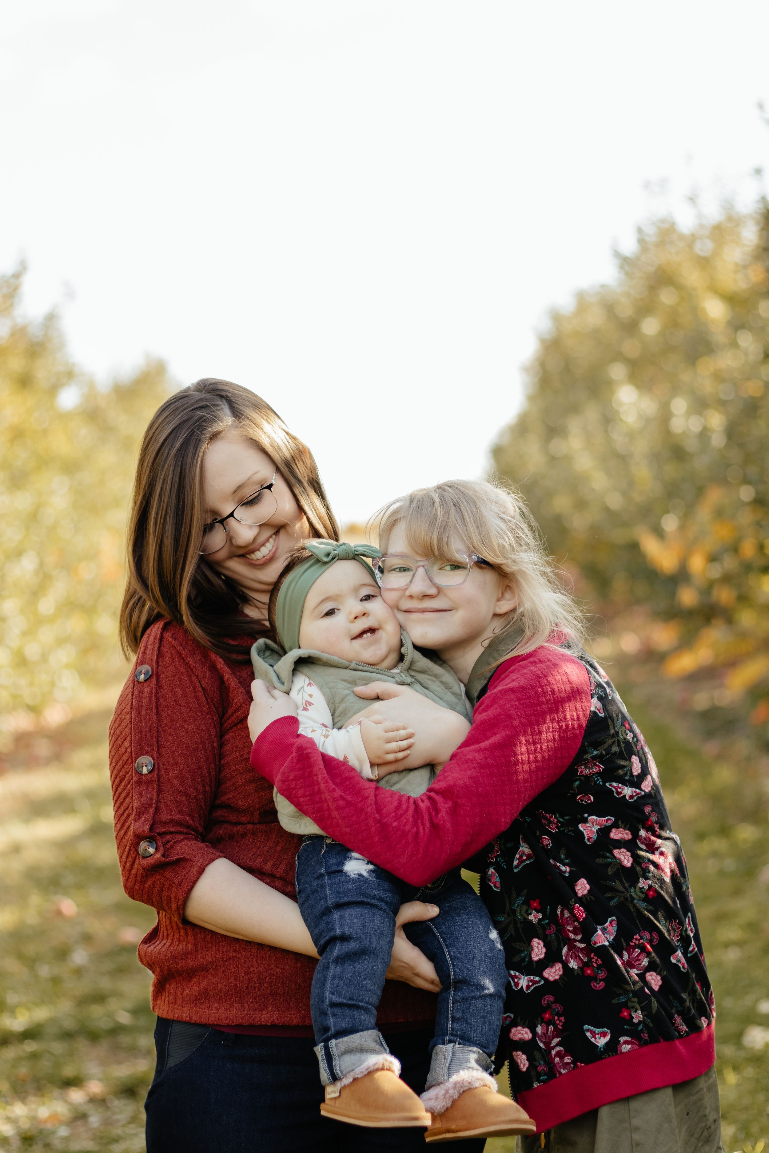 Candid moment of family members hugging and laughing together in an autumn setting.