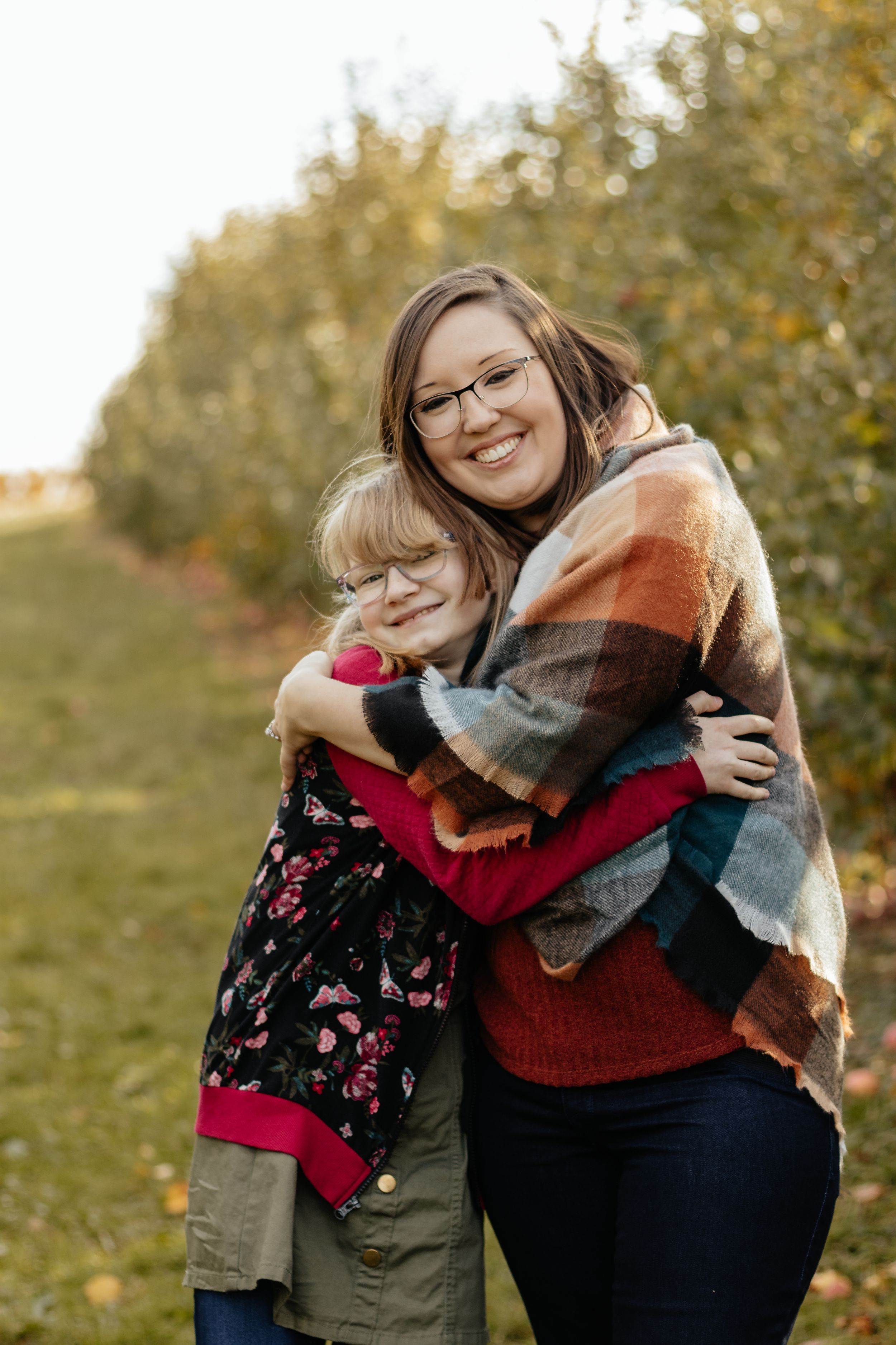 Two people share a warm embrace in an autumn orchard setting.