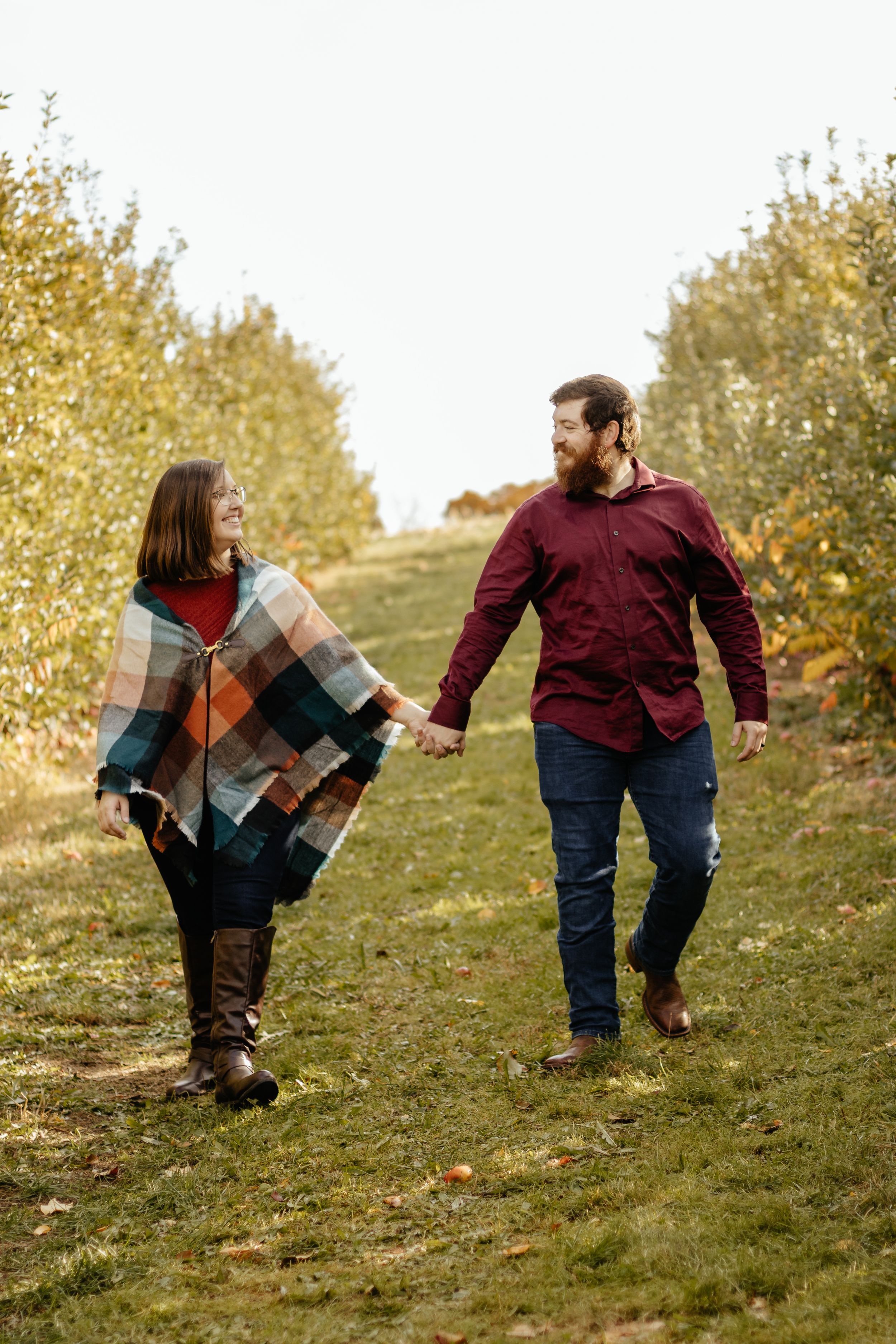 Family walking up grassy slope during golden hour photography session.