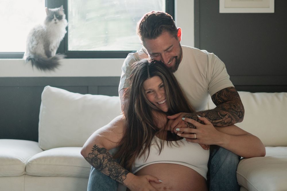 Intimate indoor maternity photos with couple relaxing on couch.