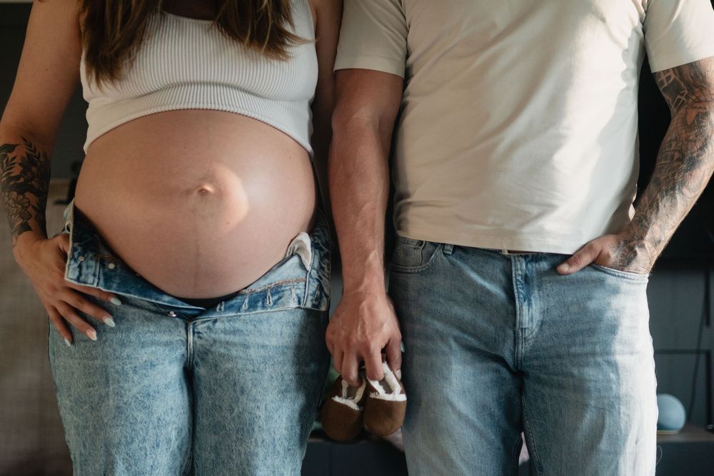 Casual maternity photos showing couple in jeans and white tops.