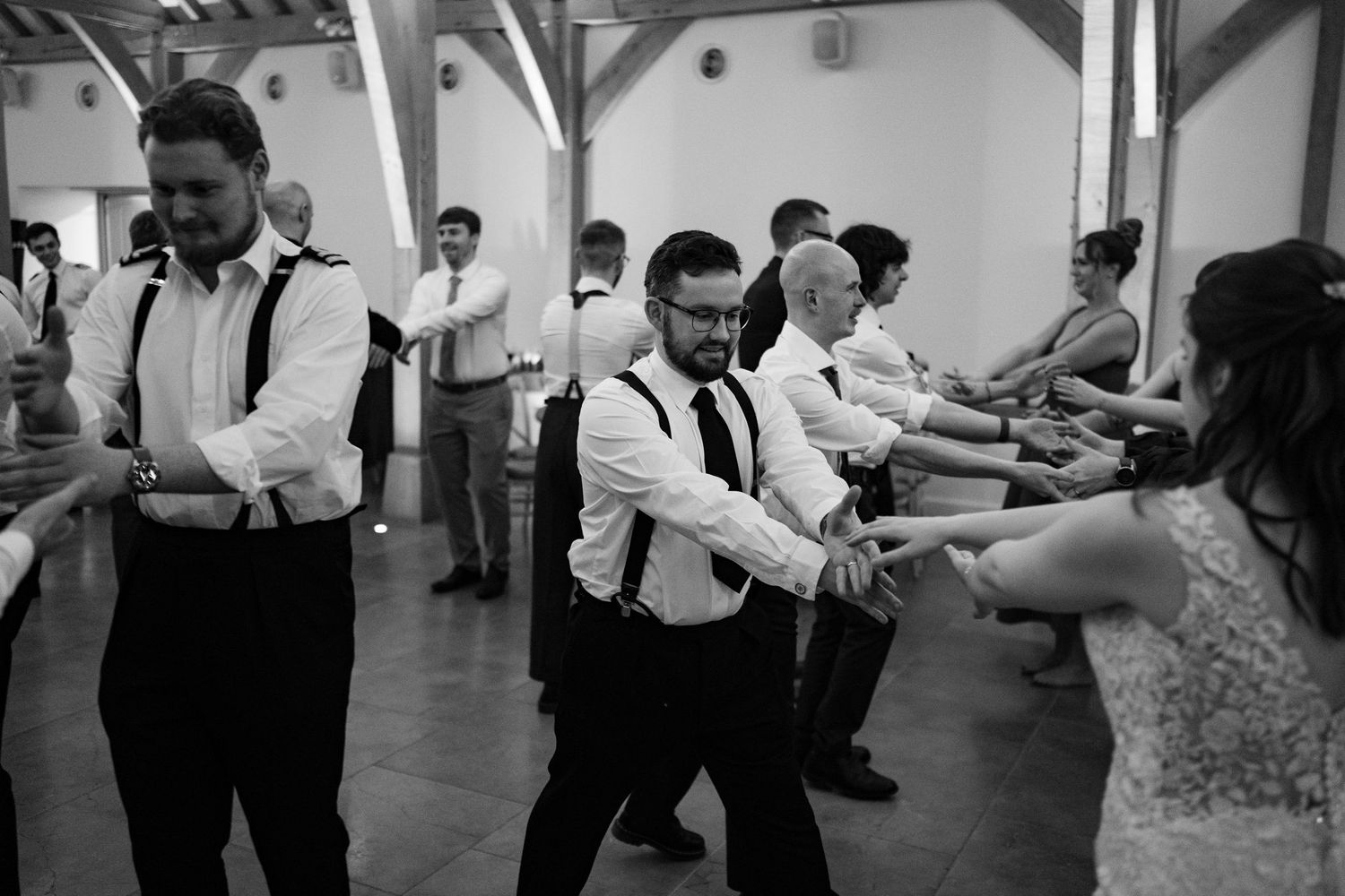 A sequence of black and white photos showing guests dancing and celebrating at a wedding reception.