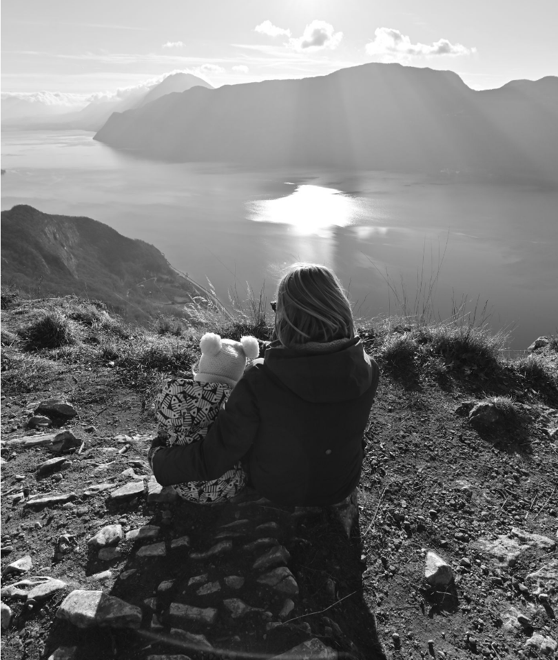 Paysage de montagne en noir et blanc avec vue panoramique sur un lac et reliefs rocheux, ambiance dramatique.