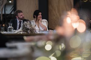 Wedding reception guests seated at elegant tables with glowing candlelight and decorative place settings.
