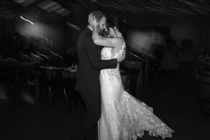 A couple in wedding attire shares a romantic dance on a dark dance floor illuminated by spotlights.